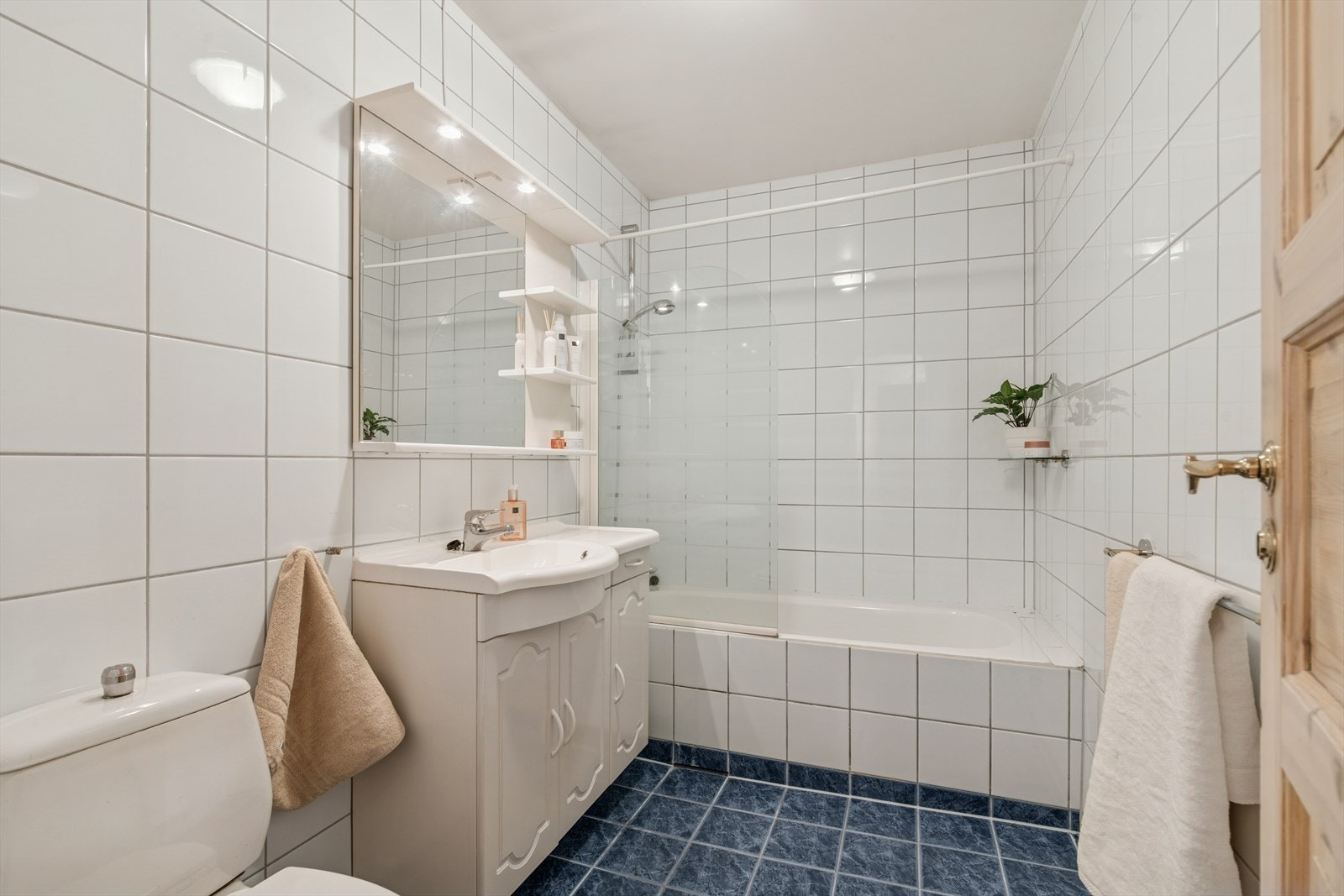 Bad innredet med toalett, servant og innfliset badekar med skjermvegg i glass. Oppgradert med overflater og innredning i 1994. Det er varmekabler i gulv Galleribilde