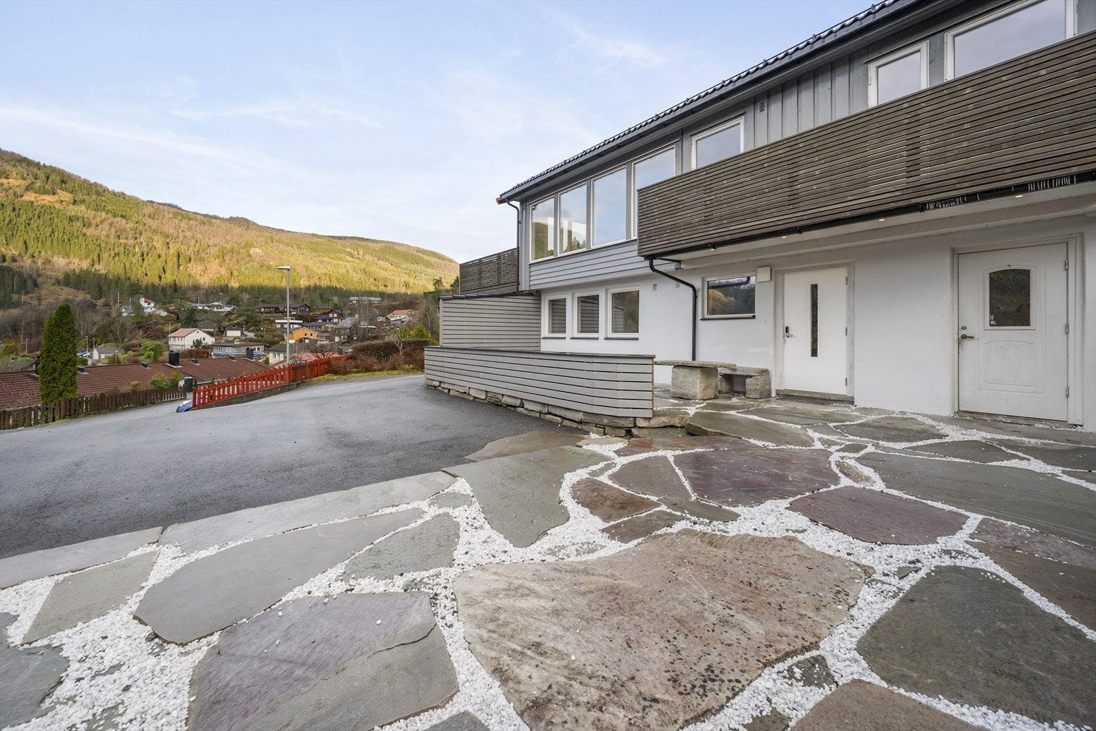 Via asfaltert parkeringsareal kjem ein fram til stort og fint tun med skiferheller og gode soltilhøve Galleribilde