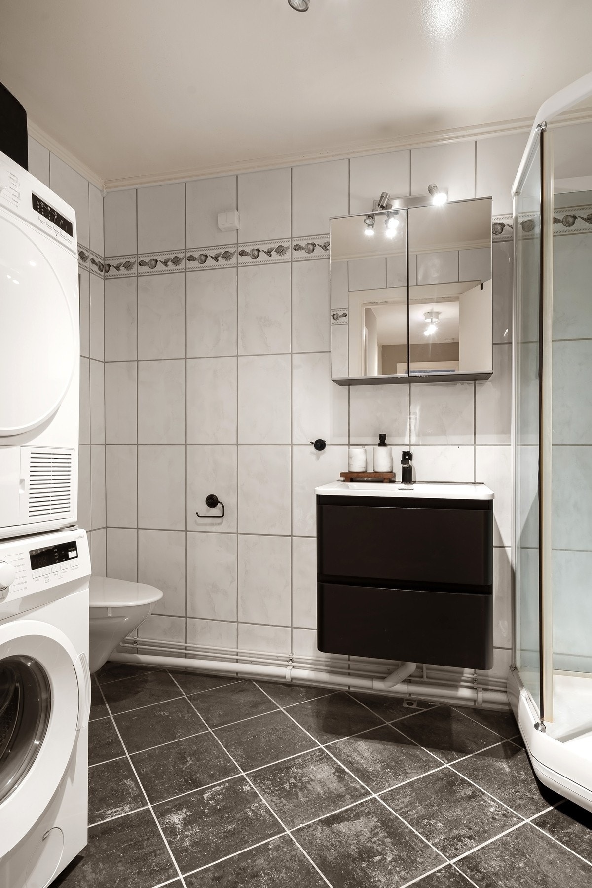 Flislagt bad med opplegg for vaskemaskin. Det er også plass til tørketrommel. Galleribilde