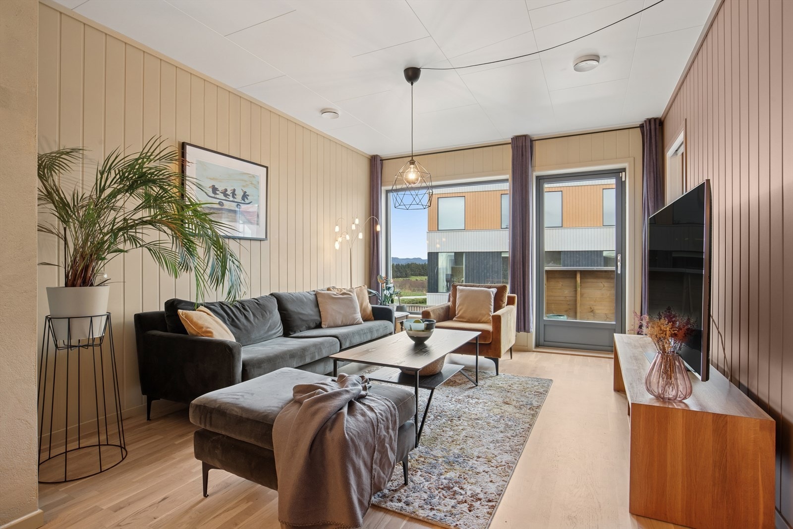 Stuen har et moderne uttrykk med varme detaljer, noe som skaper en koselig atmosfære for samlinger av nære og kjære. Galleribilde