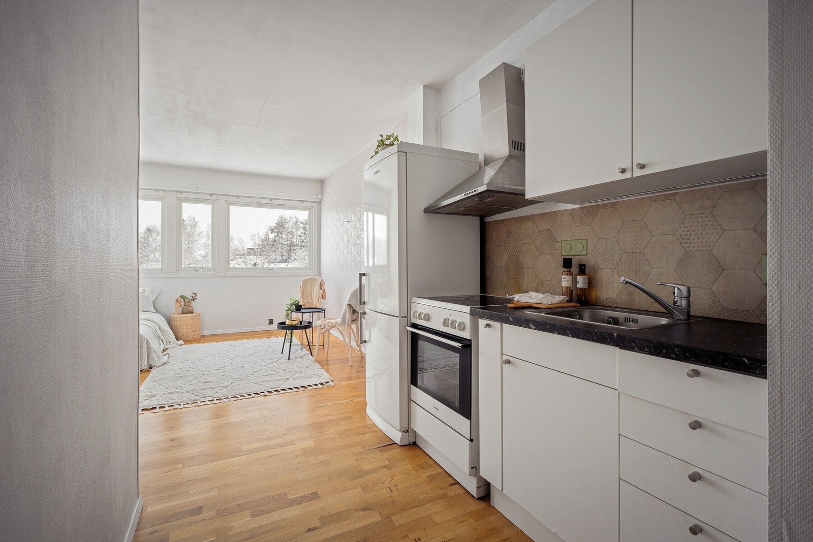 Fliser på vegg over kjøkkenbenk. Frittstående stekeovn og kjøleskap. Galleribilde