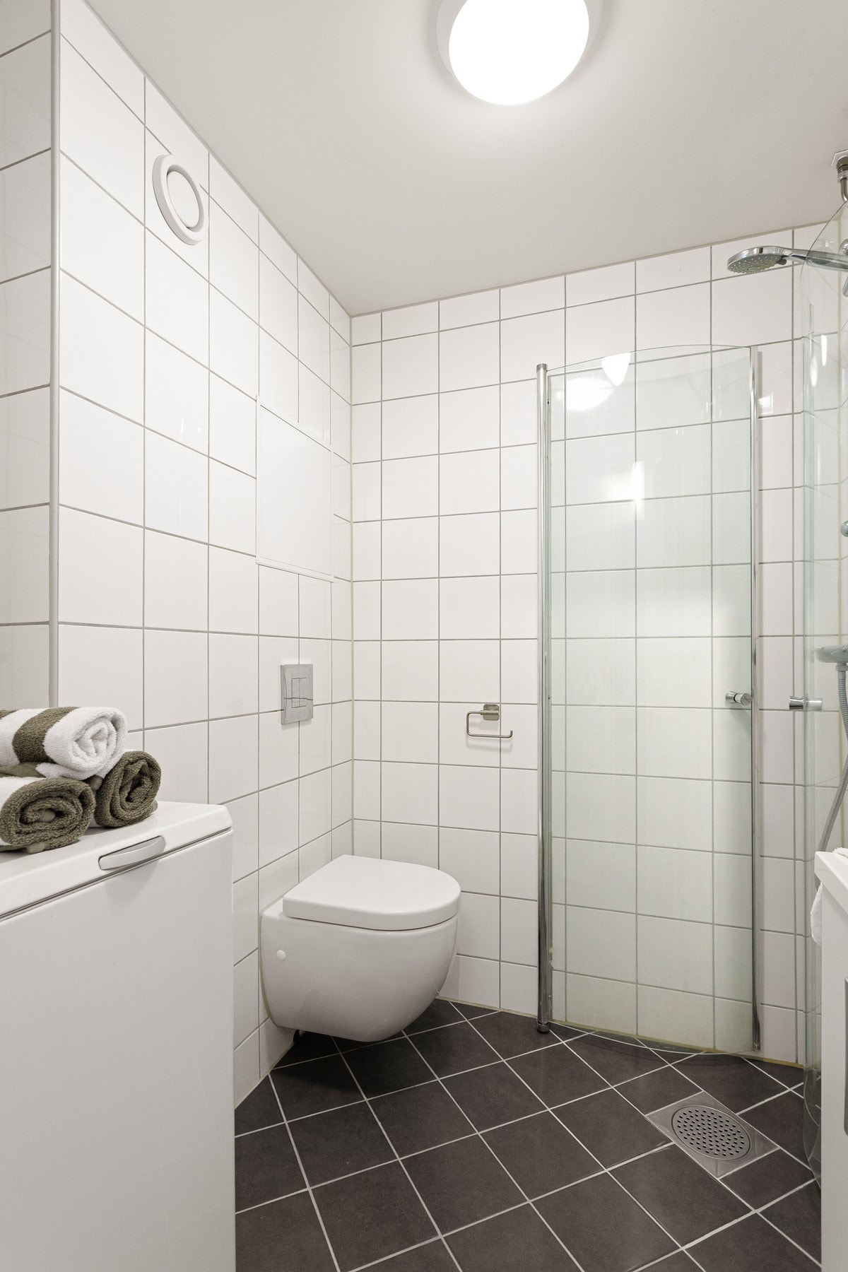 Det er baderomsinnredning med to skap, servant, samt speilskap med belysning over.. I tillegg er det vegghengt toalett og dusj med innfellbare dusjdører for å frigjøre plass på gulvet. Galleribilde