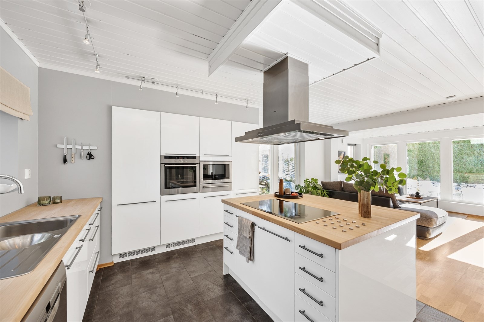 Det moderne kjøkkenet har glatte, hvite fronter og en stor kjøkkenøy. Galleribilde