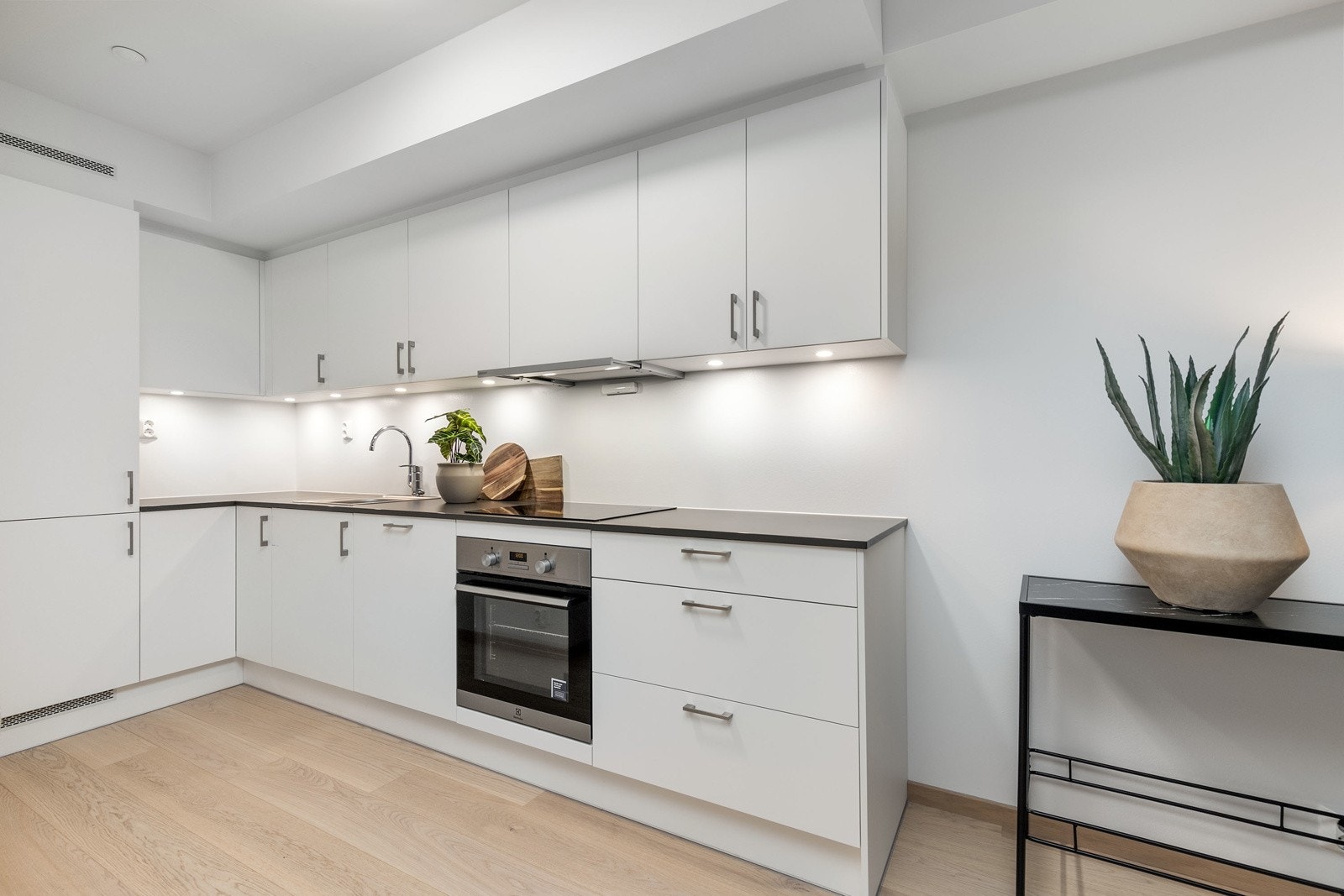 Lekkert kjøkken i åpen løsning mot stue, med integrerte hvitevarer Galleribilde