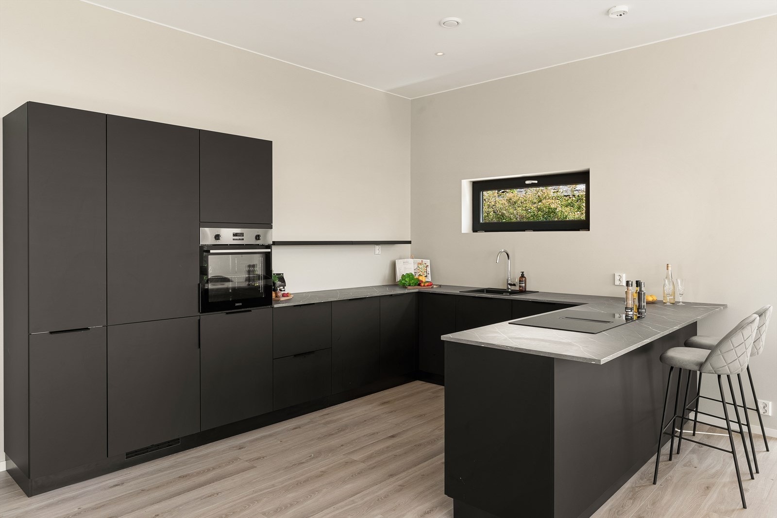 Moderne kjøkken med stilrent design, optimal utnyttelse av plass, og integrerte hvitevarer. Perfekt for matlaging for den som liker å kokkelere. Galleribilde