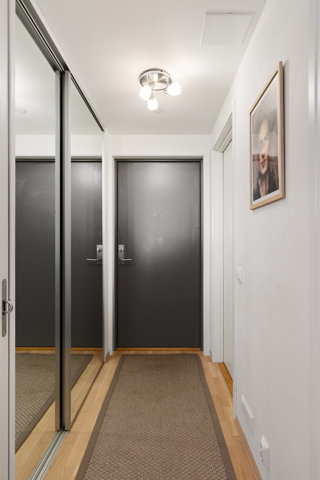 Leiligheten har en innbydende entré som gir et umiddelbart godt førsteinntrykk. Entréen er romslig og funksjonell, med god plass til oppbevaring av yttertøy i en praktisk skyvedørsgarderobe med speilfronter. Galleribilde