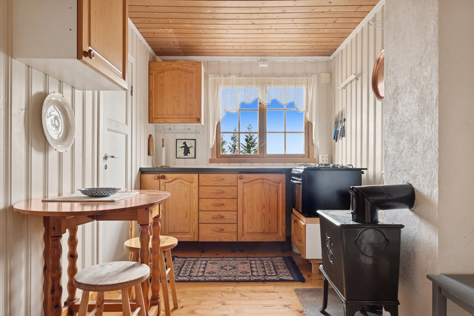 Koselig hyttekjøkken med benkeplass og utsikt mot naturen utenfor. Galleribilde