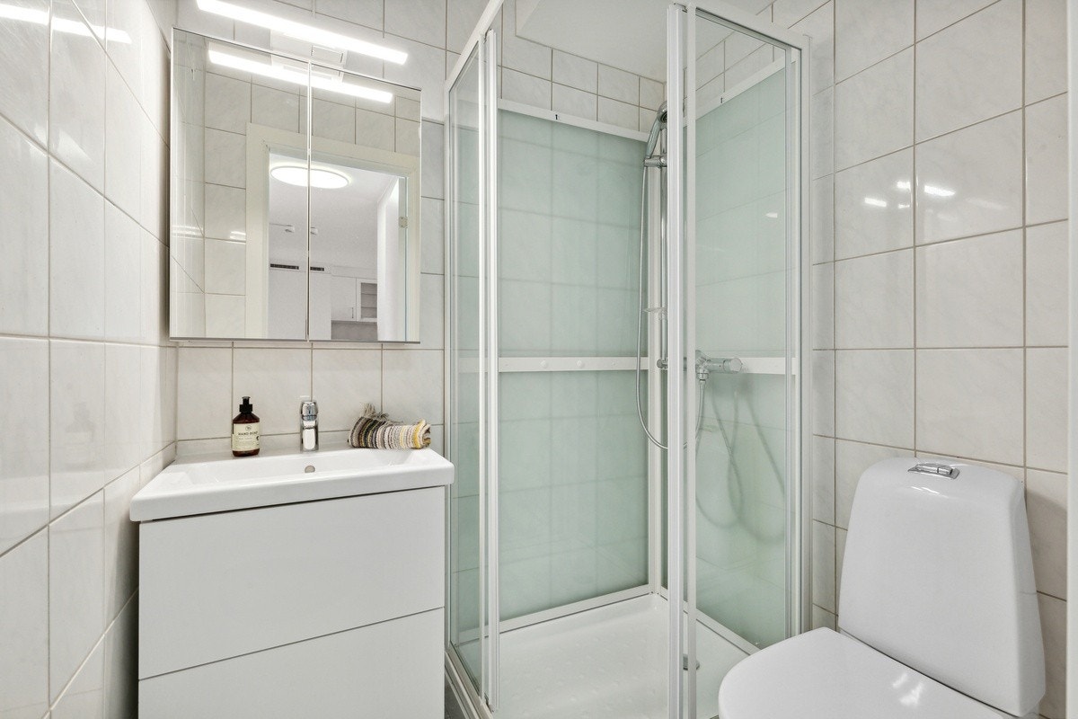 Leilighetens bad - med baderomsinnredning, dusjkabinett og WC Galleribilde