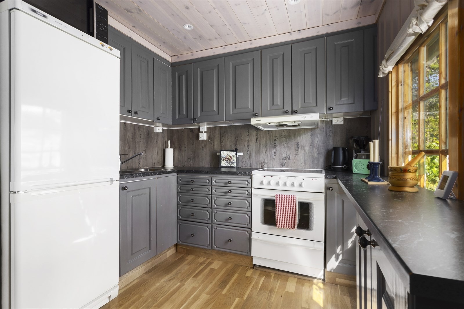 Pent kjøkken med profilerte fronter og benkeplate i laminat. Galleribilde