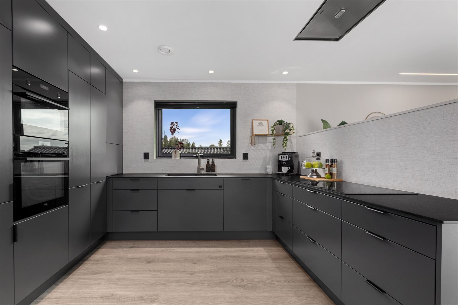 Stilrent kjøkken med integrerte hvitevarer og rikelig med skapplass. Her er kjøkkenviften integrert i taket. Galleribilde