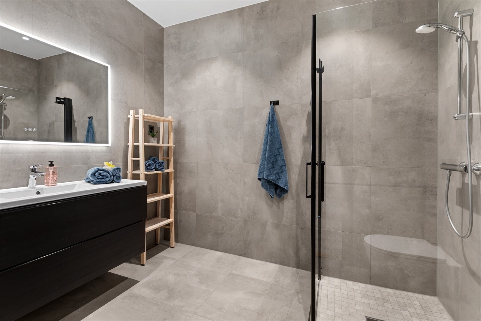 Lekker baderomsløsning med dusj, wc, servantinnredning, store fliser og moderne innredning. Galleribilde