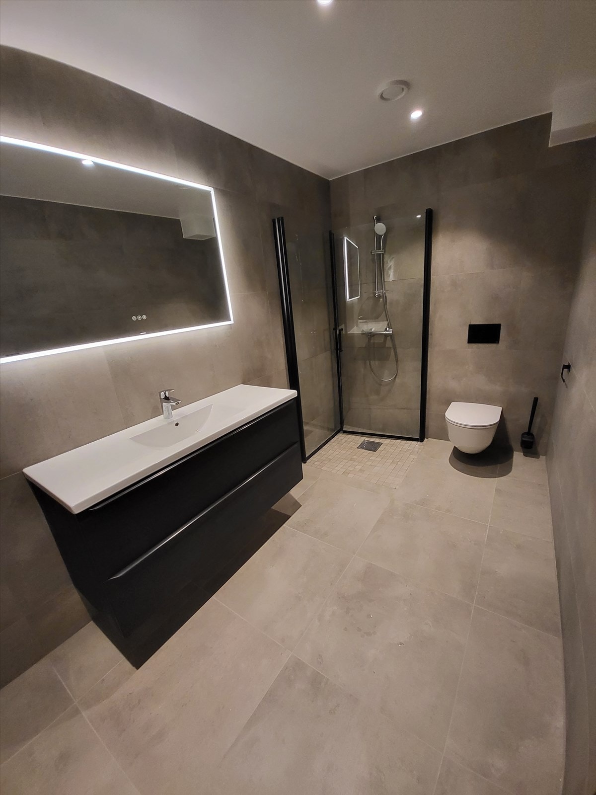 Elegant og flott flislagt bad med wc, dusj, servantinnredning og opplegg for vask/tørk. Galleribilde