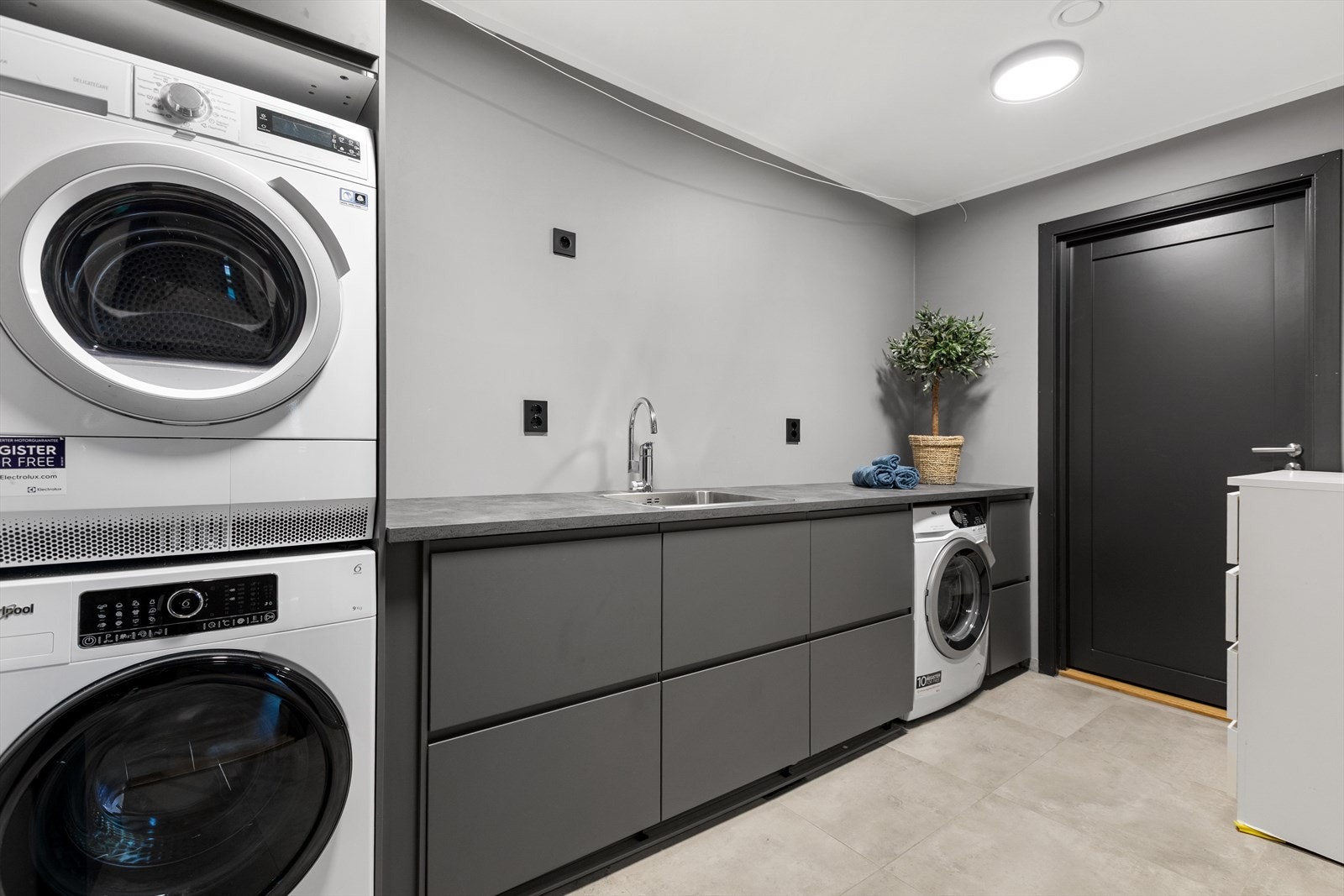 Praktisk og moderne vaskerom med god benke- og oppbevaringsplass. Dør videre ut til teknisk rom og inn til hybel med utgang. Galleribilde