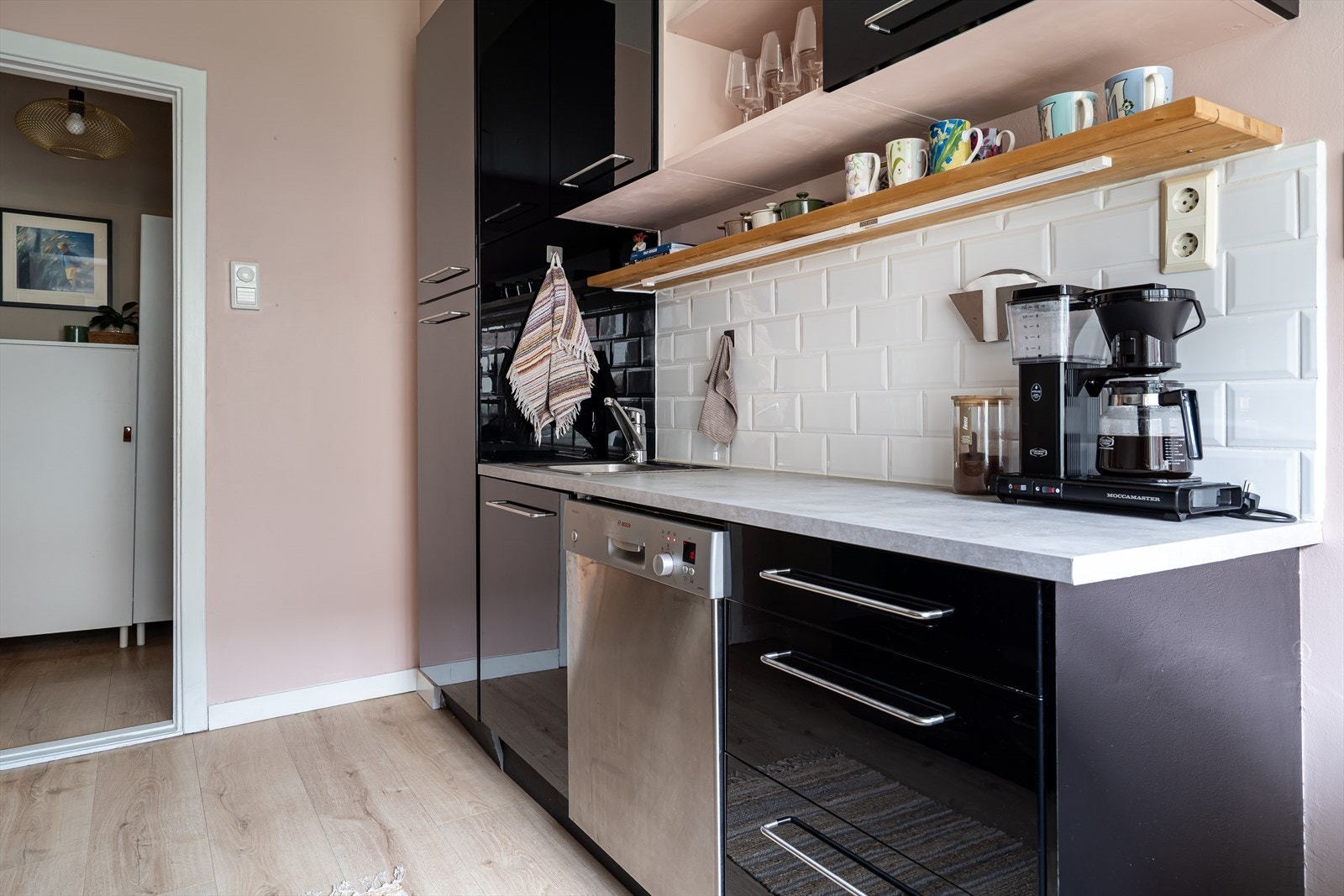 Kjøkkeninnredning består av svarte glatte, høyglans fronter og, laminert benkeplate med nedfelt kum i rustfritt stål. Galleribilde