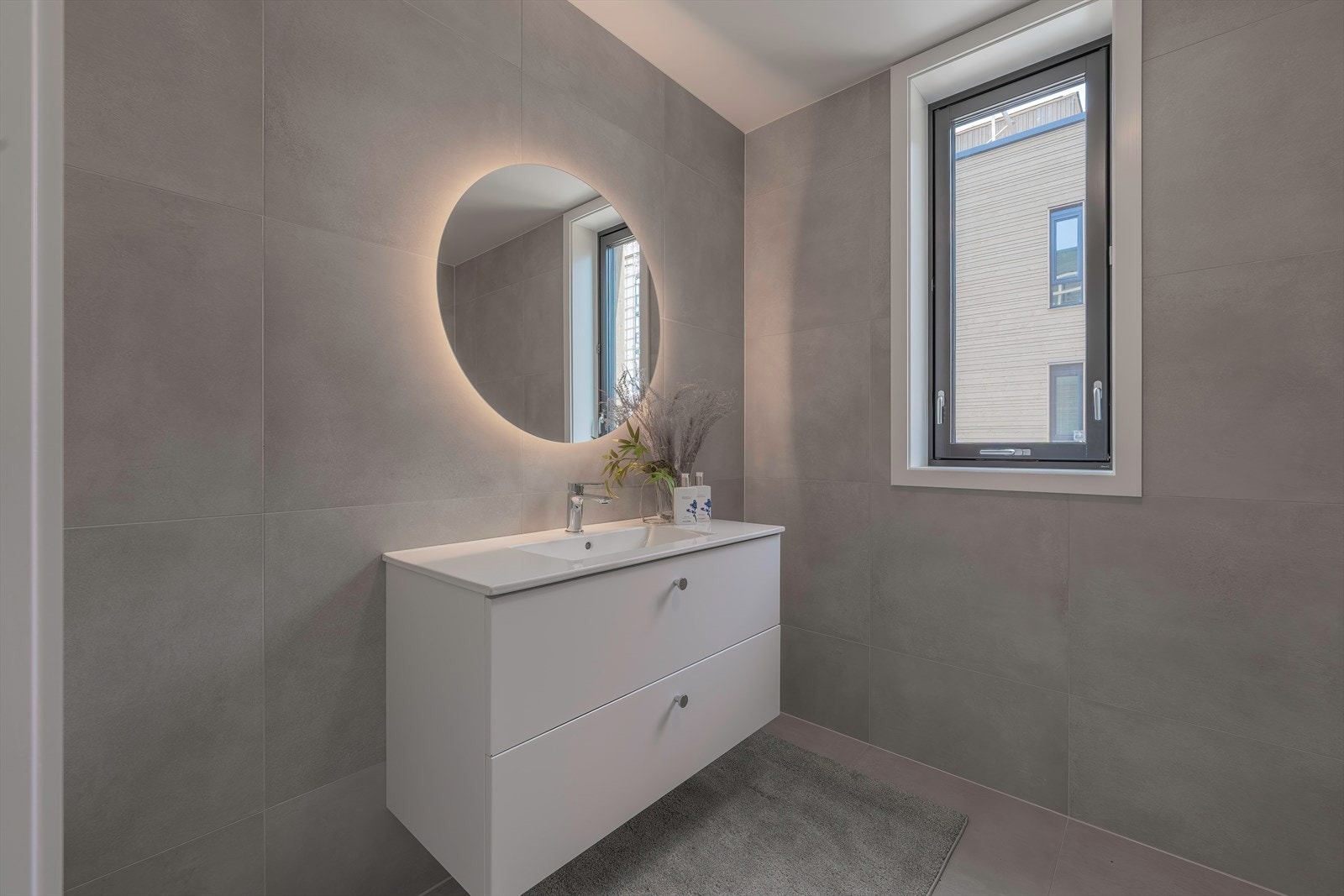 Fliselagt bad med pen baderomsinnredning, toalett og dusj Galleribilde