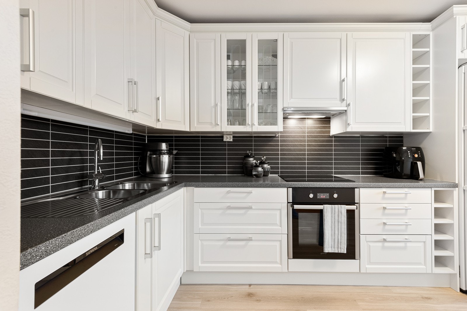 Skapinnredningen består av profilerte fronter i malt MDF, kombinert med laminert benkeplate og beskyttende laminatplate på vegg over benk. Av integrerte hvitevarer medfølger platetopp og stekeovn. Galleribilde