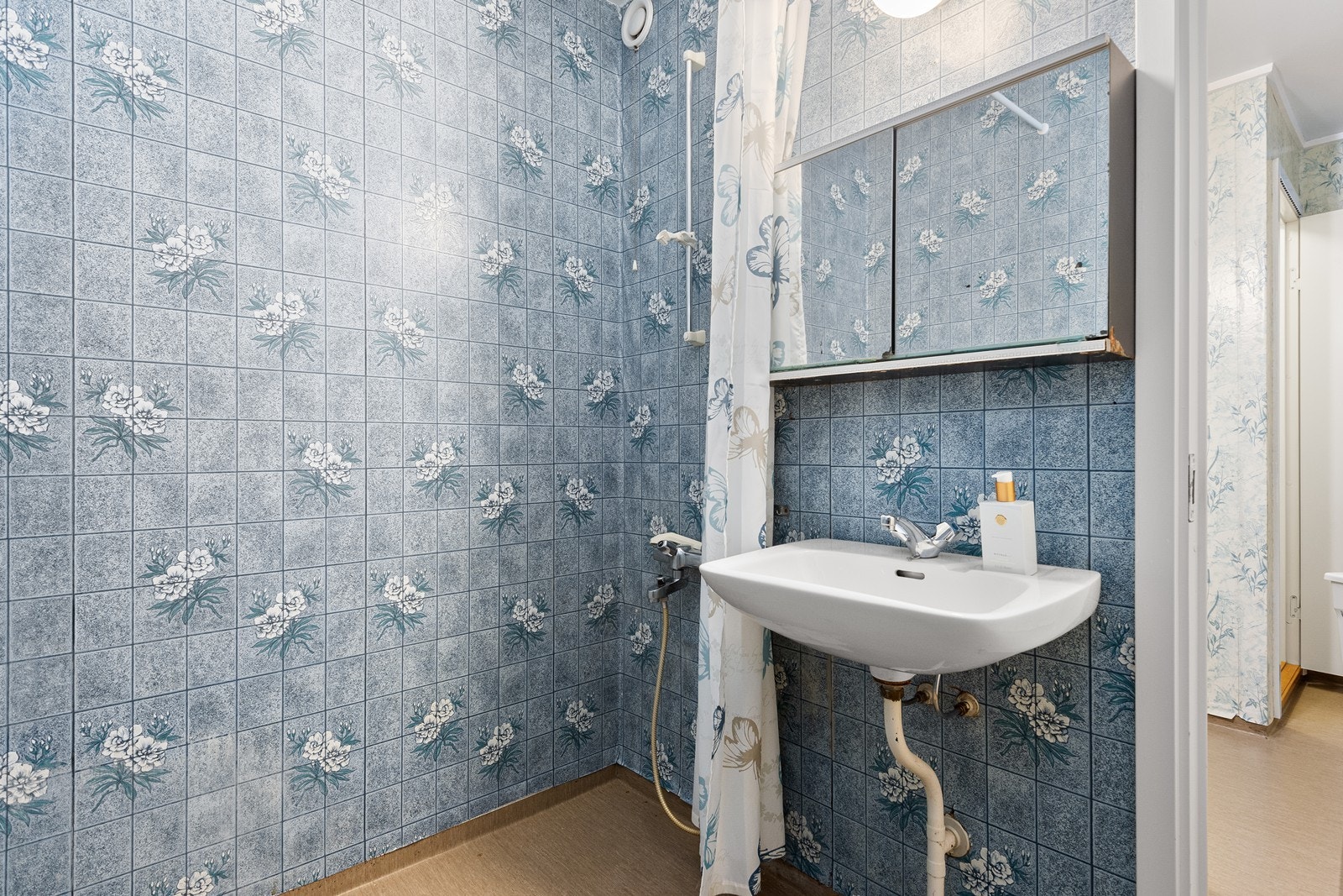 Badet er innredet med dusjnisje med dusjforheng og vask. Galleribilde