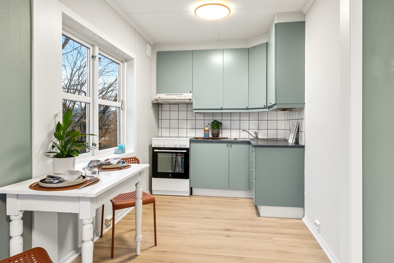 Kjøkken malt i samme farge som vegg og med plass til spisebord. Galleribilde