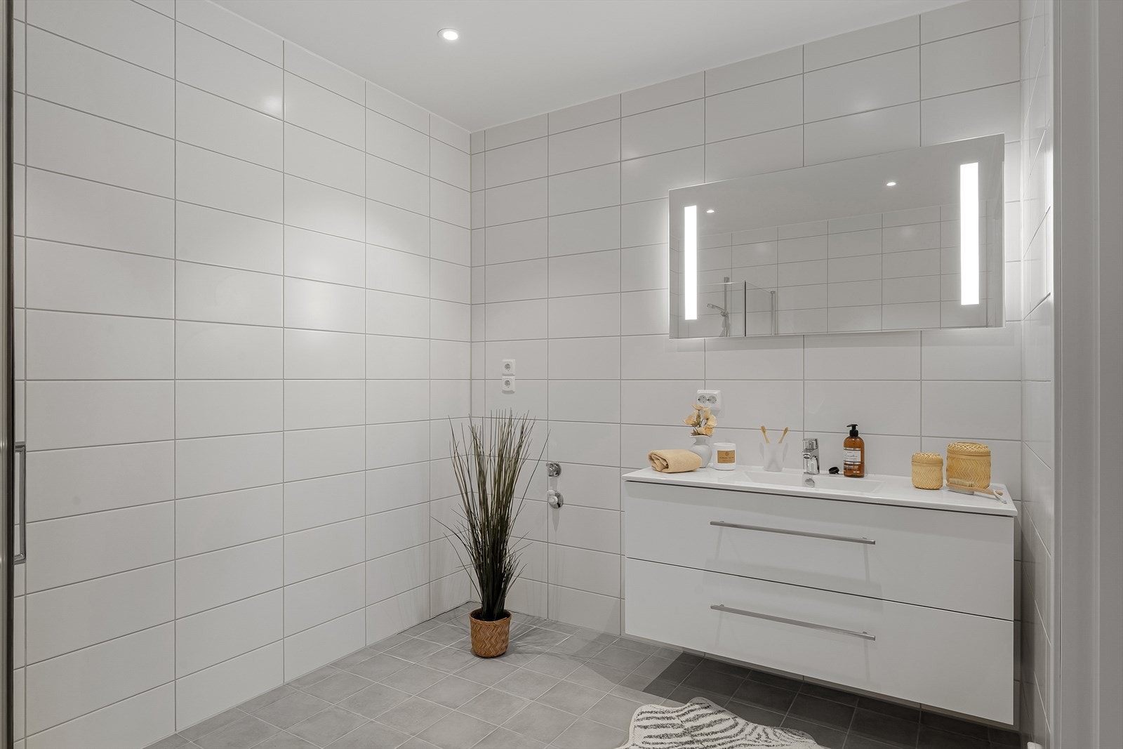 Helfliset bad med wc, dusjhjørne og varme i gulv for ekstra komfort. Badet fremstår som arealeffektivt med baderomsinnredning i hvit utførelse. Galleribilde