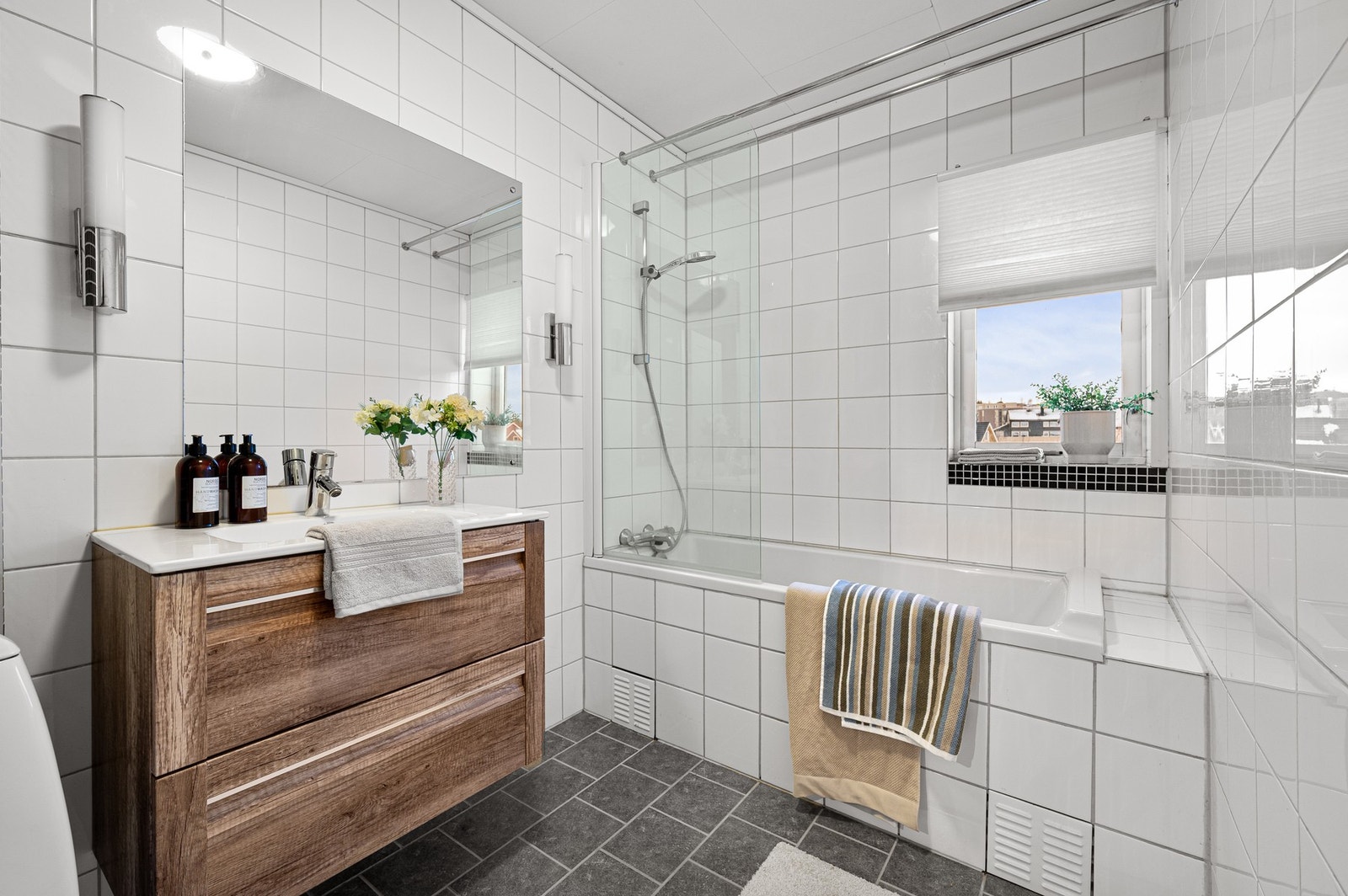 Baderommet er flislagt og har innredning med servant, speil og badekar med dusjløsning. Galleribilde