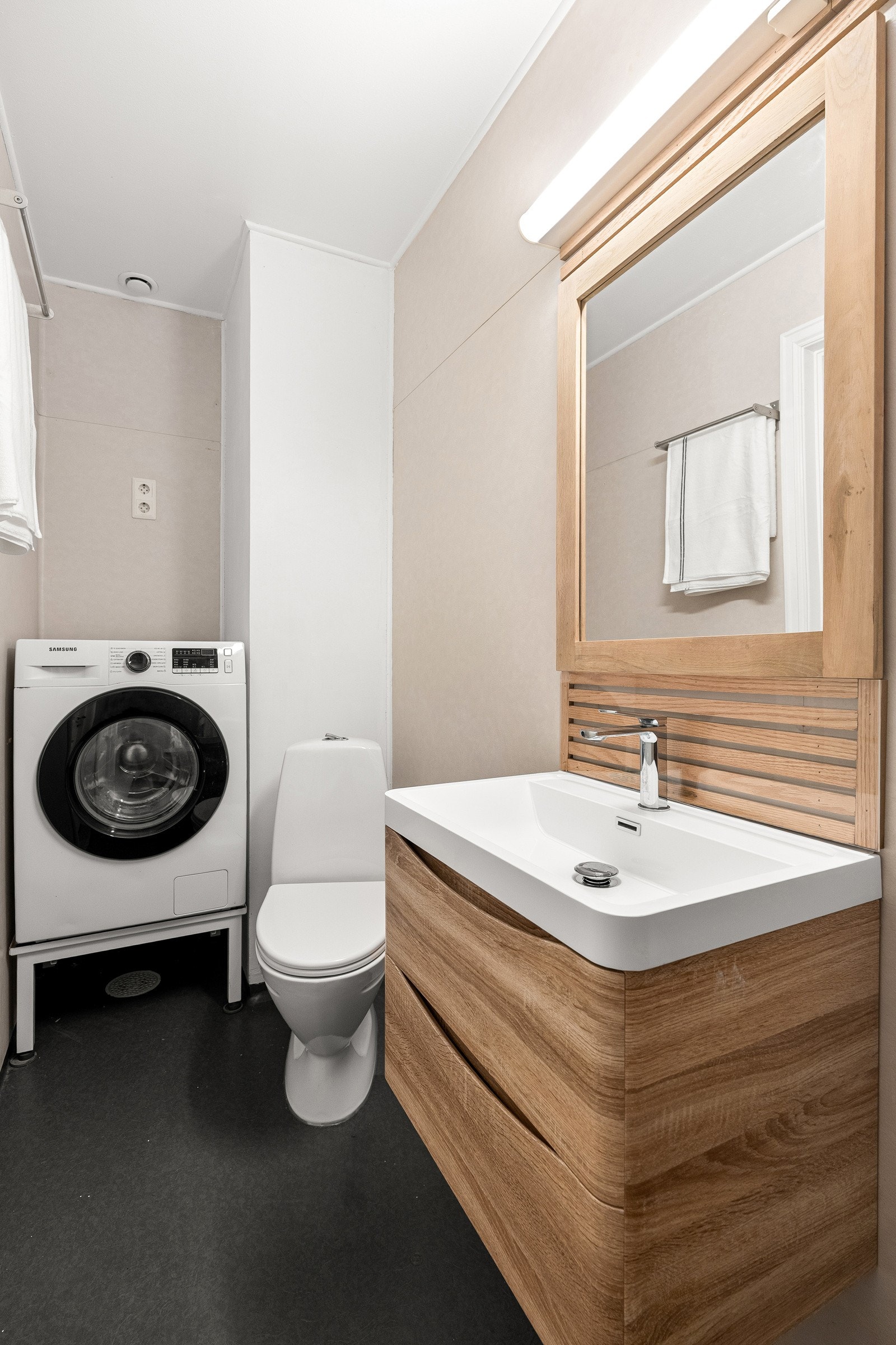 Badet er stilrent og funksjonelt, med servant, dusj og toalett, i tillegg til praktisk opplegg for vaskemaskin. Galleribilde