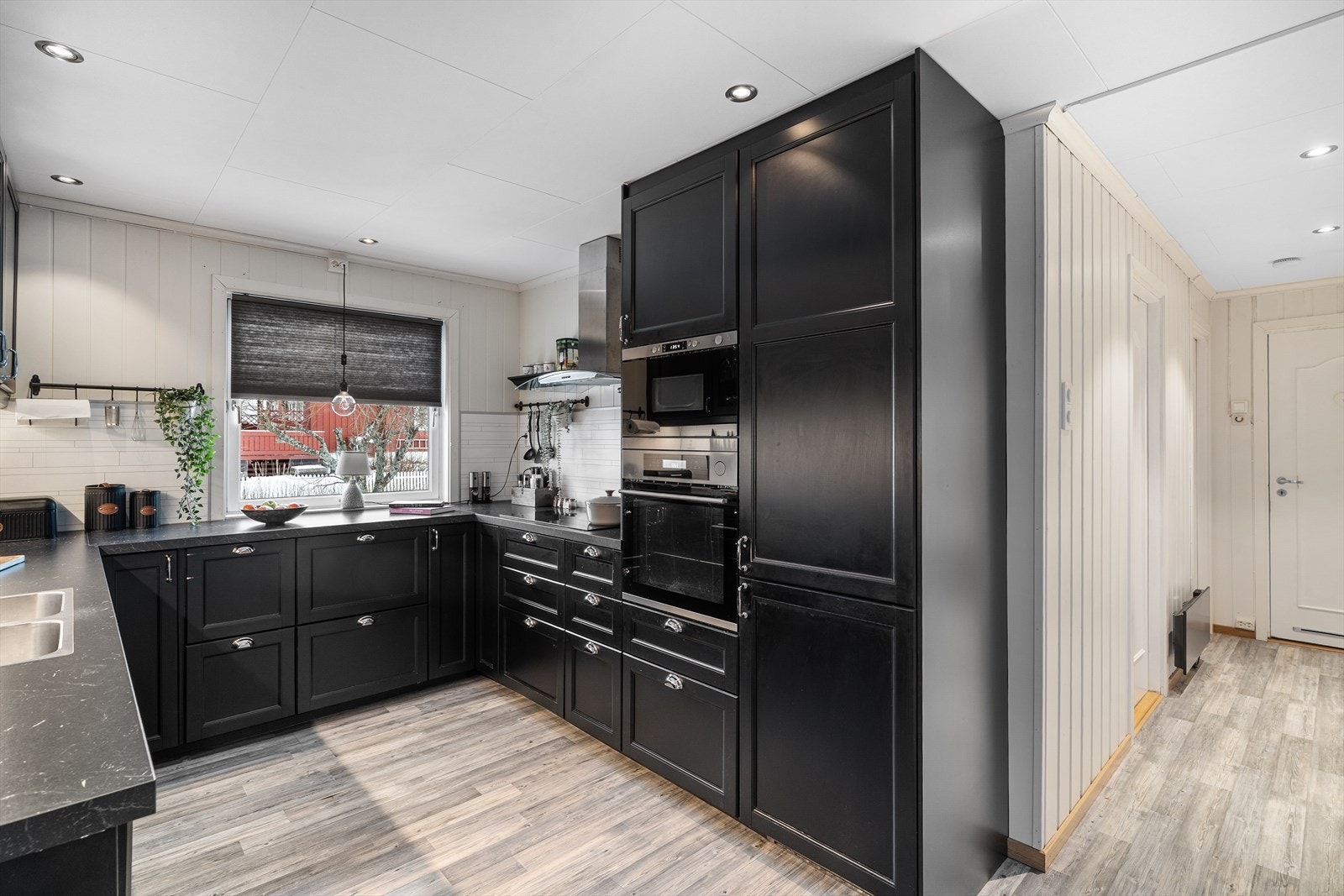 Kjøkkeninnredning med både høyskap, overskap og benkeskap - Folierte skrog med profilerte fronter og laminert benkeplate - Integrerte hvitevarer er kombiskap, komfyr, mikrobølgeovn, oppvaskmaskin, platetopp og ventilator. Galleribilde