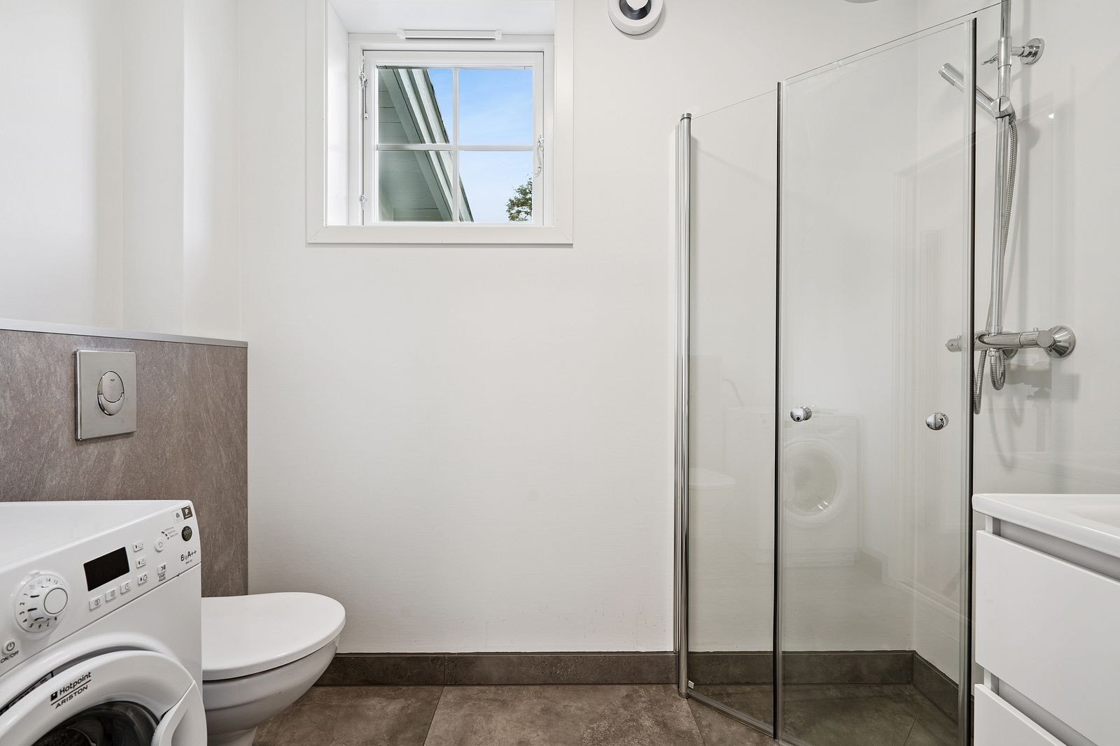 Lekkert bad/WC med dusjhjørne, vegghengt WC og vaskemaskin Galleribilde