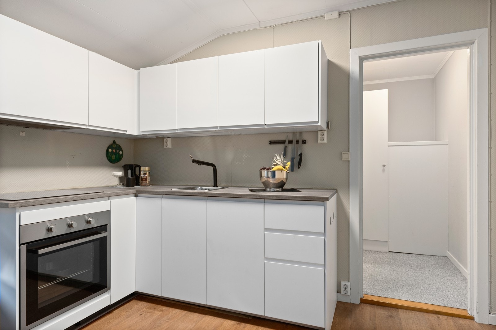 Kjøkken har hvit innredning med slette fronter, vinkel kjøkken med laminat benkeplate og skapplass både i over og underskap. Galleribilde