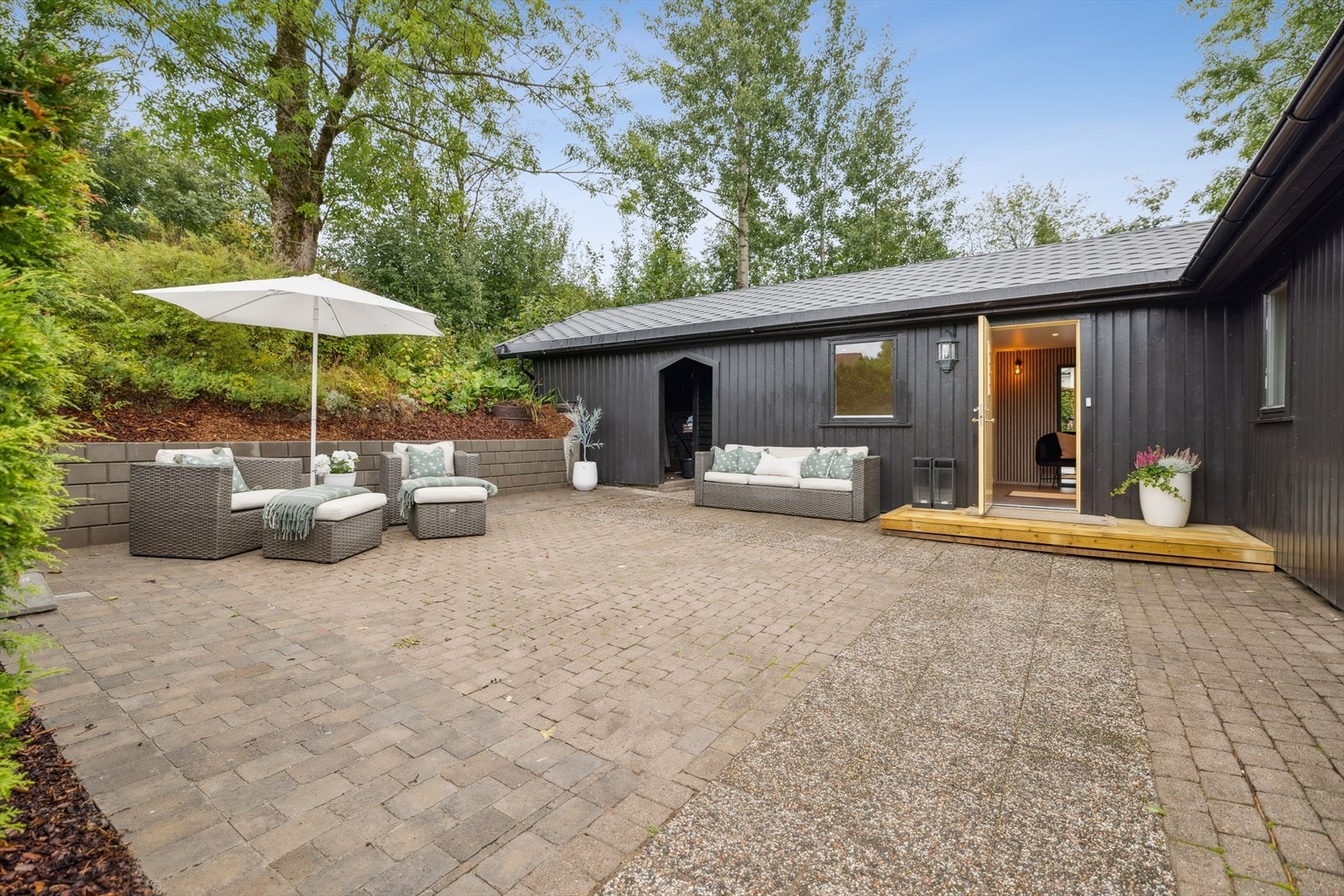 Et lunt og trivelig inngangsparti. På oversiden av uteplassen er det en gruset gårdsplass. Galleribilde