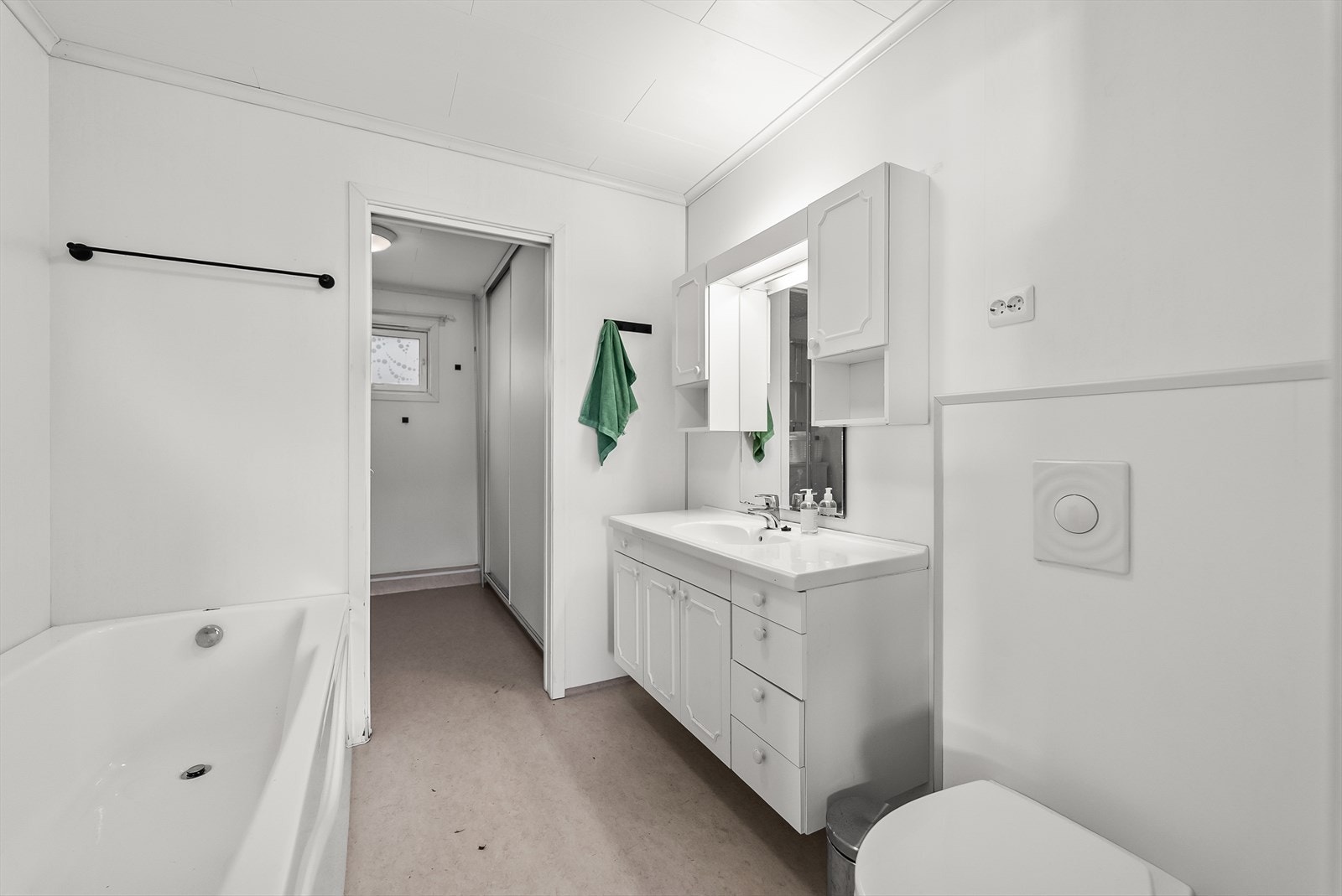 Kombinert bad og vaskerom med naturlig deling. Badet er innredet med baderomsinnredning, toalett og badekar. Skyvedør inn til vaskerom med garderobeplass. Galleribilde