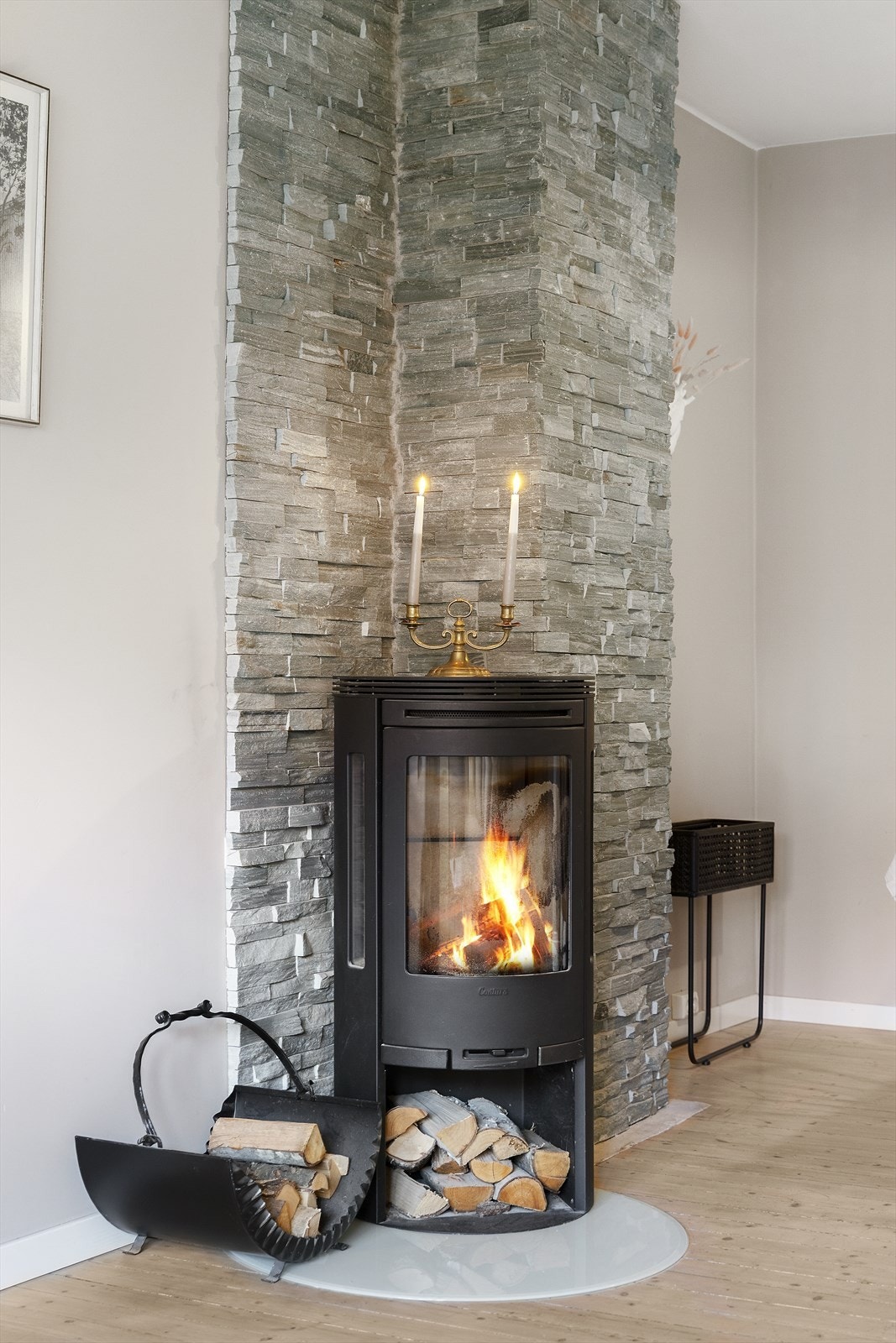 Sjarmerende peisovn med glassdør på ildfast plate i stue. Galleribilde