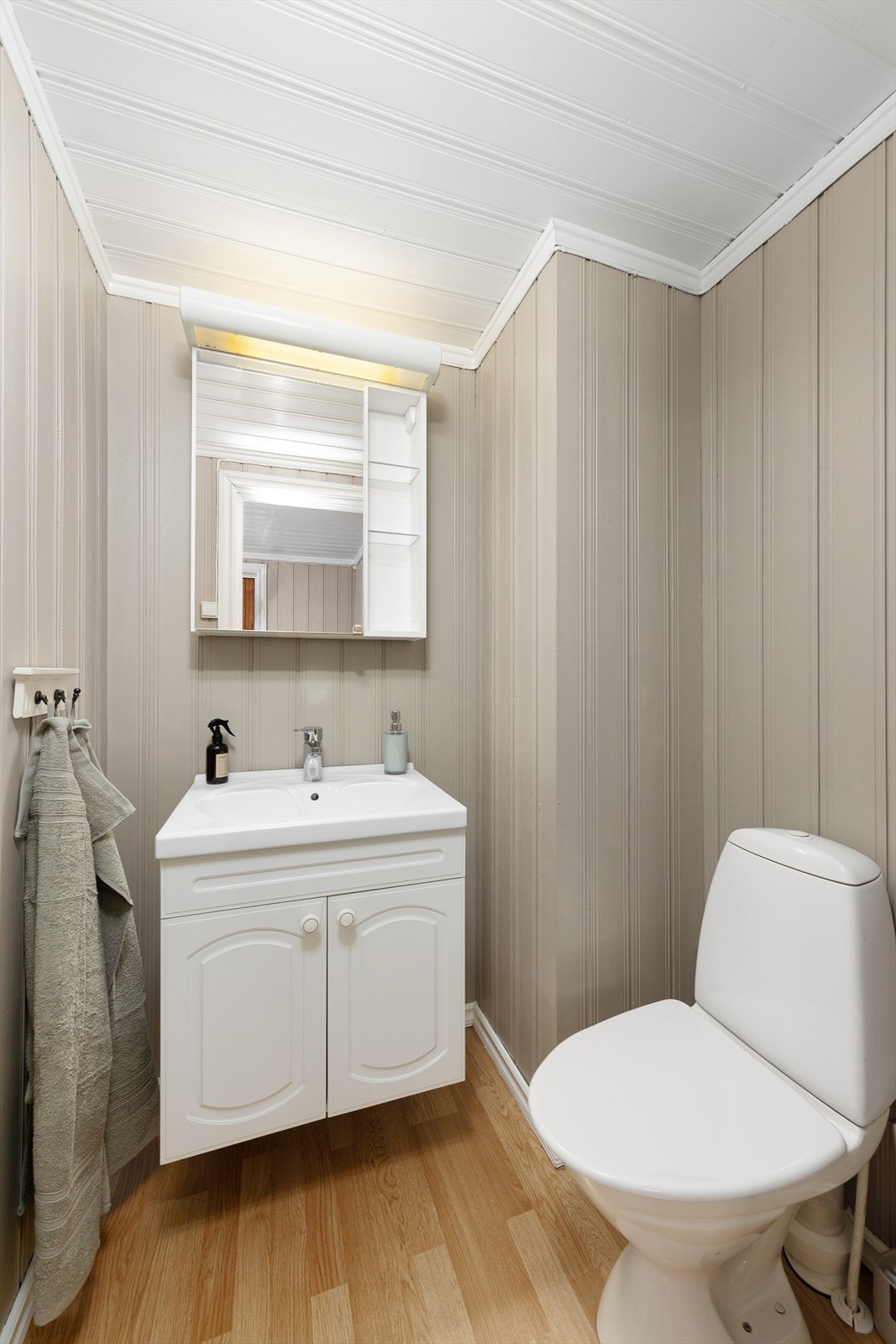 Enkelt innredet toalettrom med servantinnredning og toalett. Galleribilde