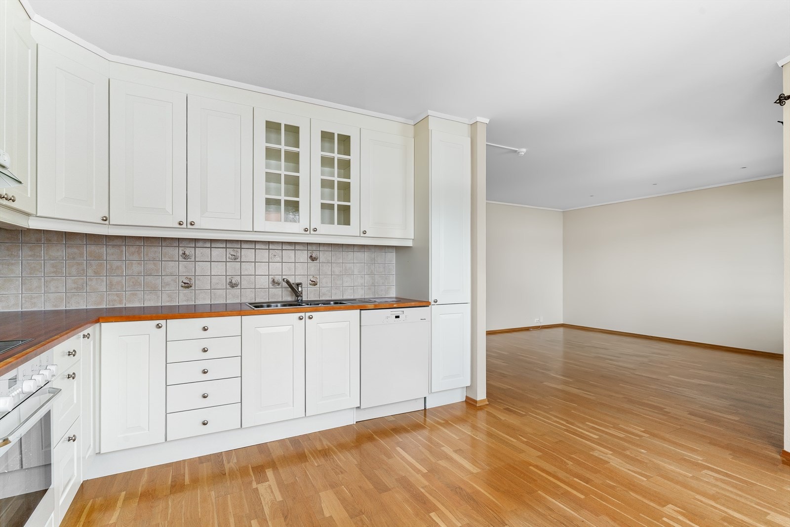 Klassisk, eldre kjøkkeninnredning med hvite profilerte fronter og benkeplate av laminat. Galleribilde