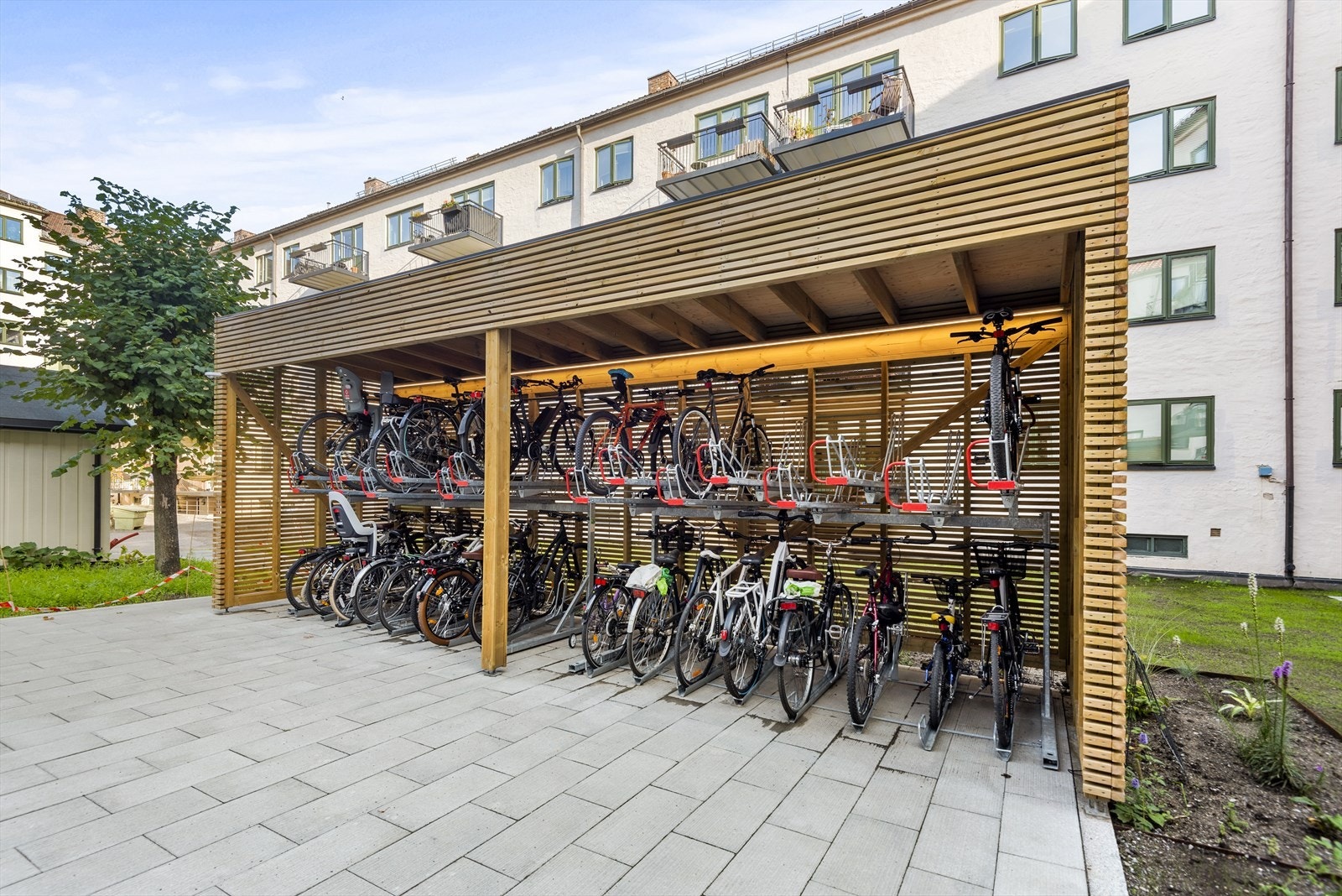 Praktisk sykkelparkering, slik at sykkelen slipper å ta opp plass i boden. Sykkelskuret er satt opp i nyere tid og var en del av en større oppgradering av felles bakgård. Galleribilde