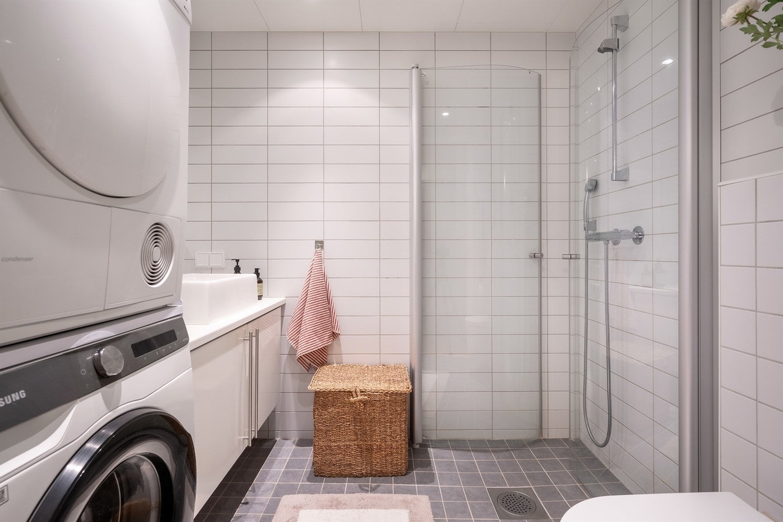 Badet er flislagt på gulv og vegger med elektriske varmekabler. Badet er innredet med dusj på gulv med dusjdører i herdet glass, servant med skapinnredning, klosett med vegghengt klosettskål og innebygget sisterne. Galleribilde