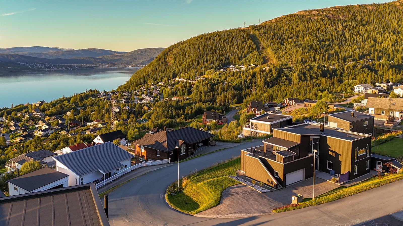 Man får ett solid førsteinntrykk av boligen ved ankomst, da det er brosteinbelagt innkjørsel og parkeringsplasser. Hagen er også opparbeidet med prydbusker, plen og forstøtningsmurer. Trappen fører til en svært stor og delvis overbygd terrasse. Galleribilde