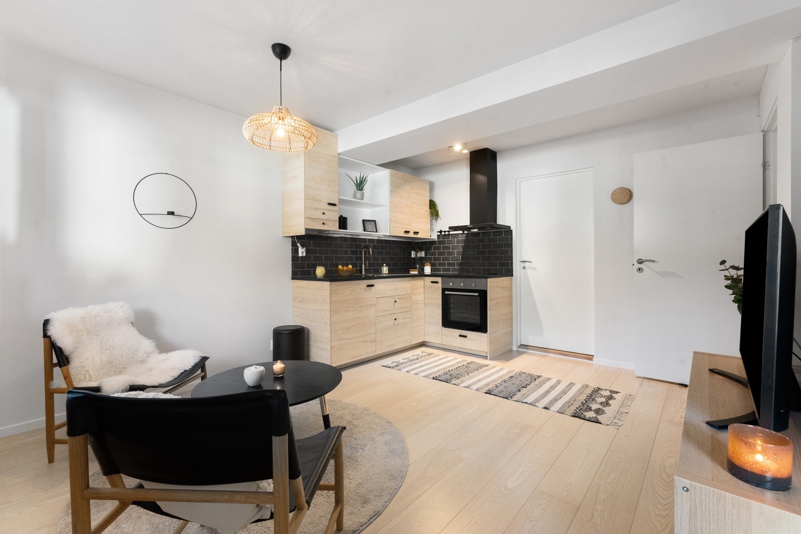 Slette fronter og benkeplate av laminat, med integrerte hvitevarer som platetopp, komfyr og kjøleskap. Galleribilde