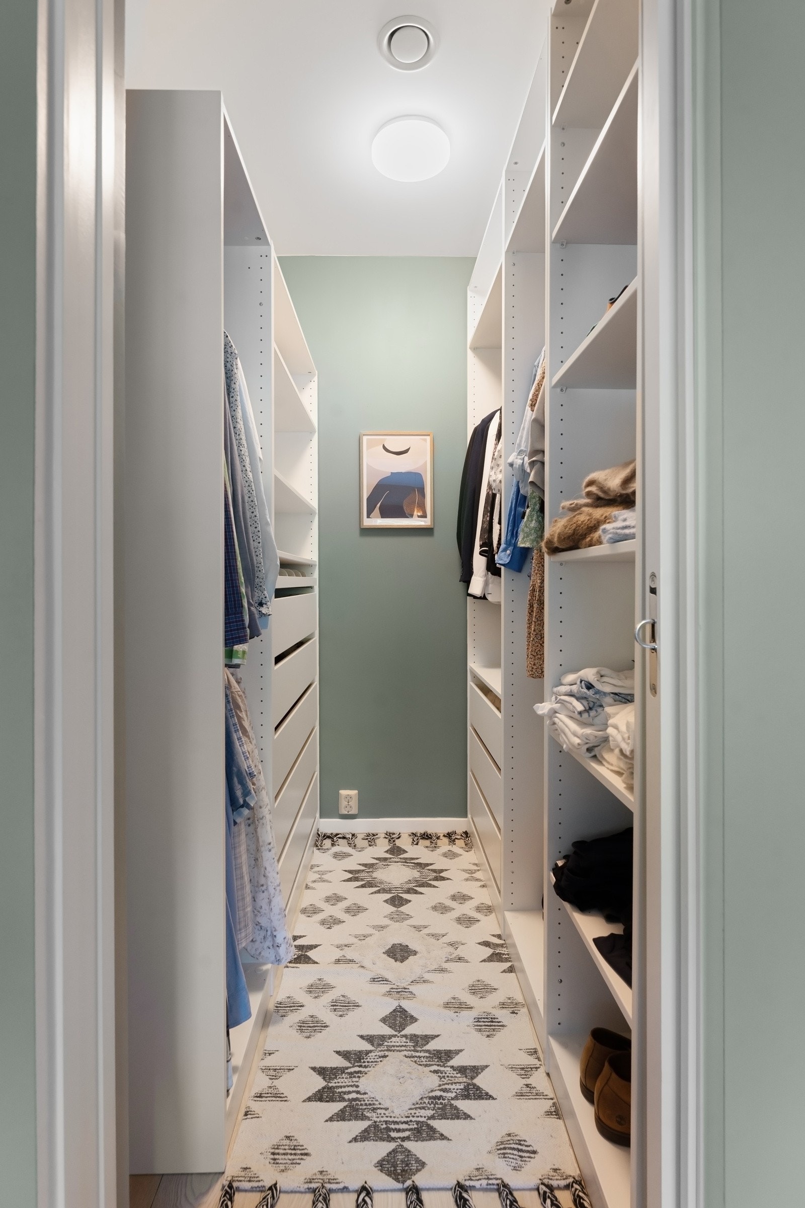 Omkledningsrom med åpne garderobestammer langs begge sider av rommet. Galleribilde