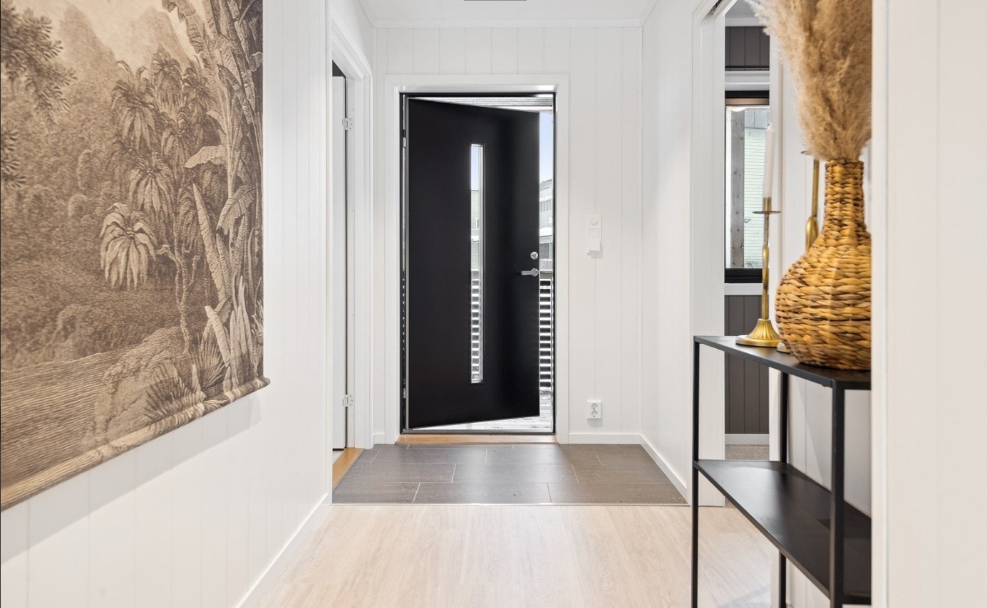 Lys entré med flislagt inngangspart med overgang til laminat. Galleribilde