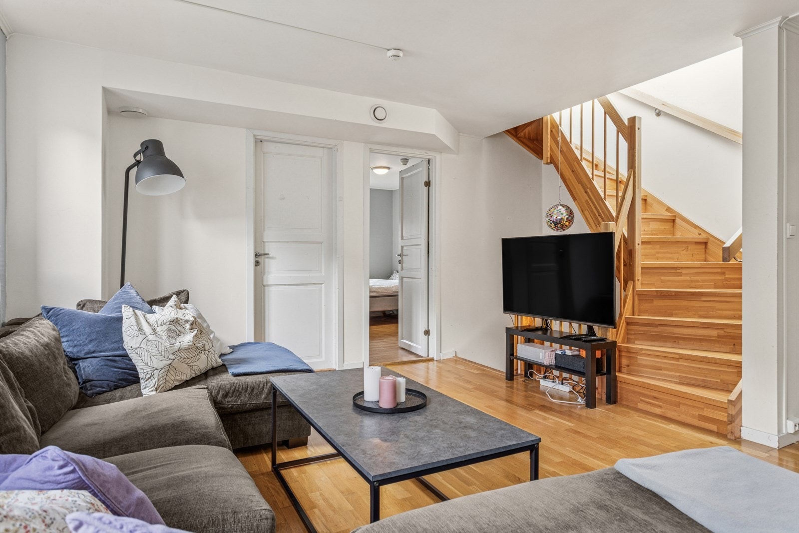 Trappen i tre gir en naturlig forbindelse til loftsetasjen og bidrar til rommets helhet. TV-området er praktisk plassert for underholdning og avslapning. Galleribilde