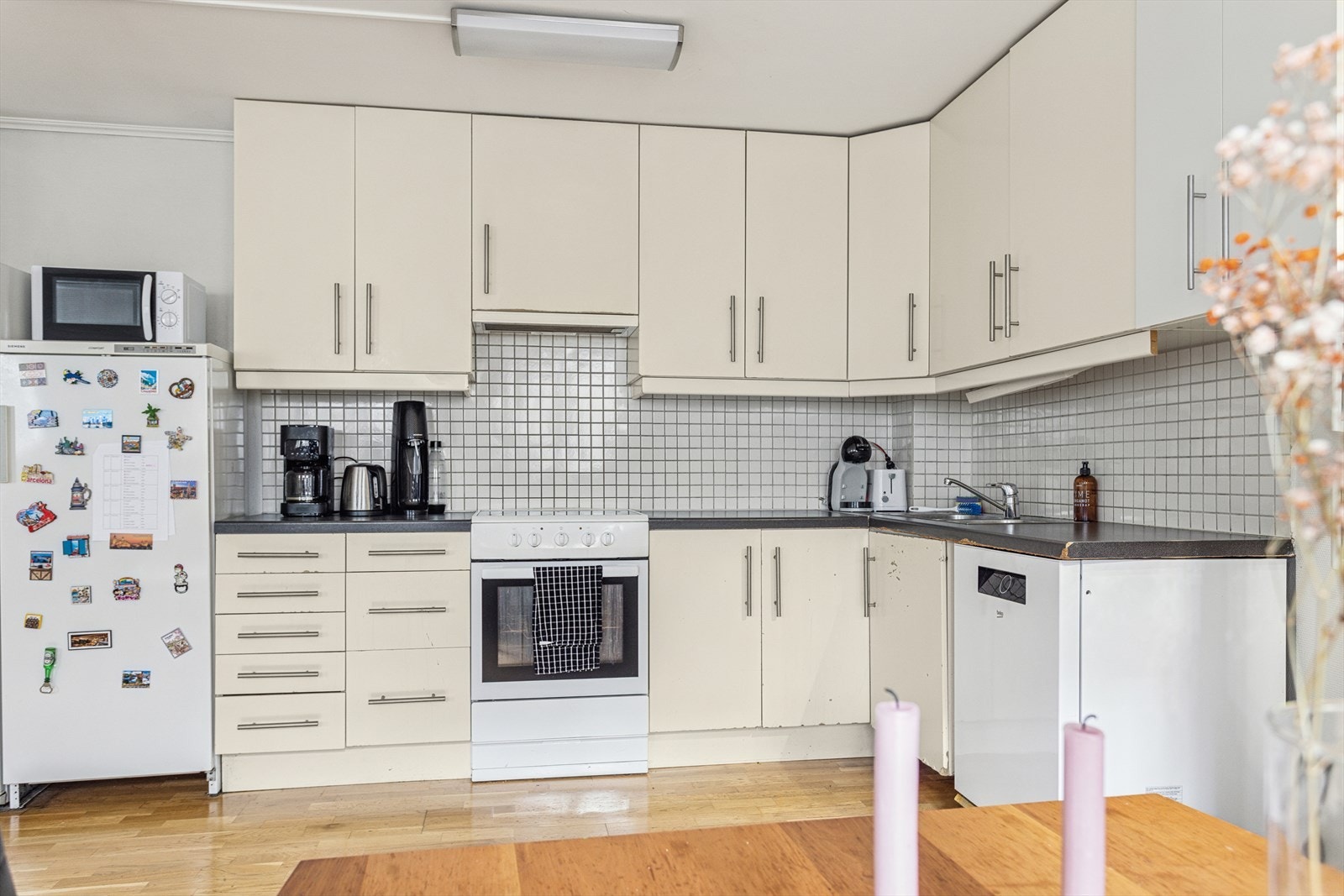 Kjøkkenet har en praktisk innredning med lyse fronter og integrerte hvitevarer. Flislagt bakvegg gir en lettstelt overflate bak komfyr og vask. Galleribilde