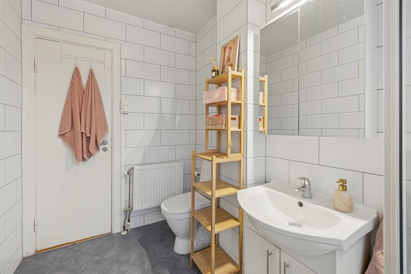 Badet er innredet med servant med underskap, speil med tilhørende belysning, gulvmontert toalett og dusjkabinett. Galleribilde