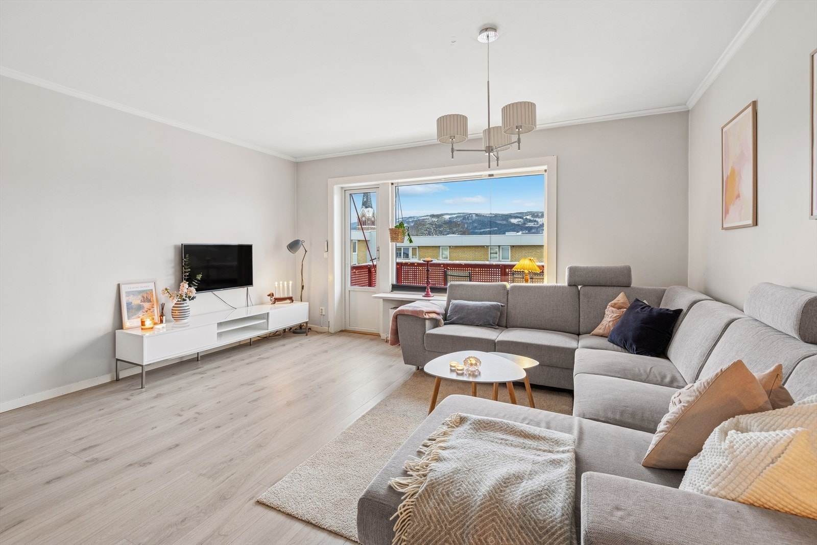 Innbydende stue med god plass til sofa og spisebord. Det er laminat på gulvet, lyse overflater og radiator som oppvarmingskilde. Galleribilde