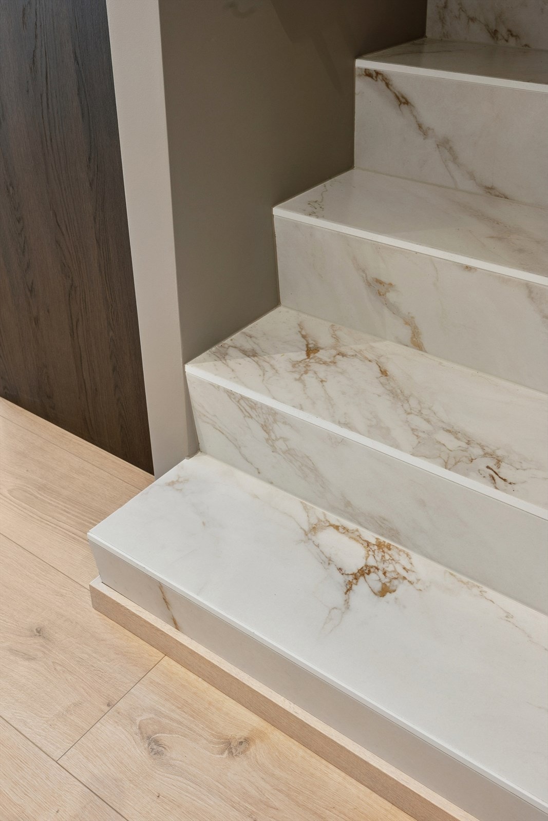Elegant trappeløp med eksklusive fliser i marmorert utførelse som understreker boligens gjennomgående moderne preg. Galleribilde