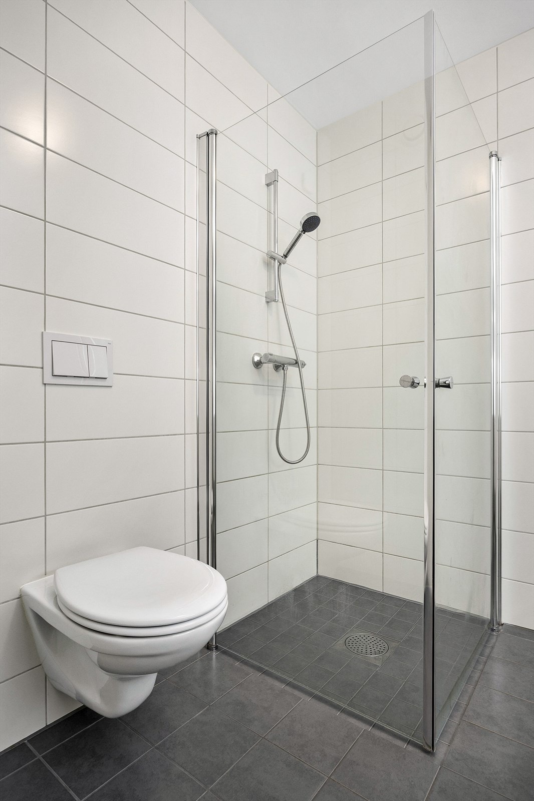 Videre har badet veggmontert toalett, dusjhjørne med innfellbare glassdører og opplegg for vaskemaskin. Galleribilde