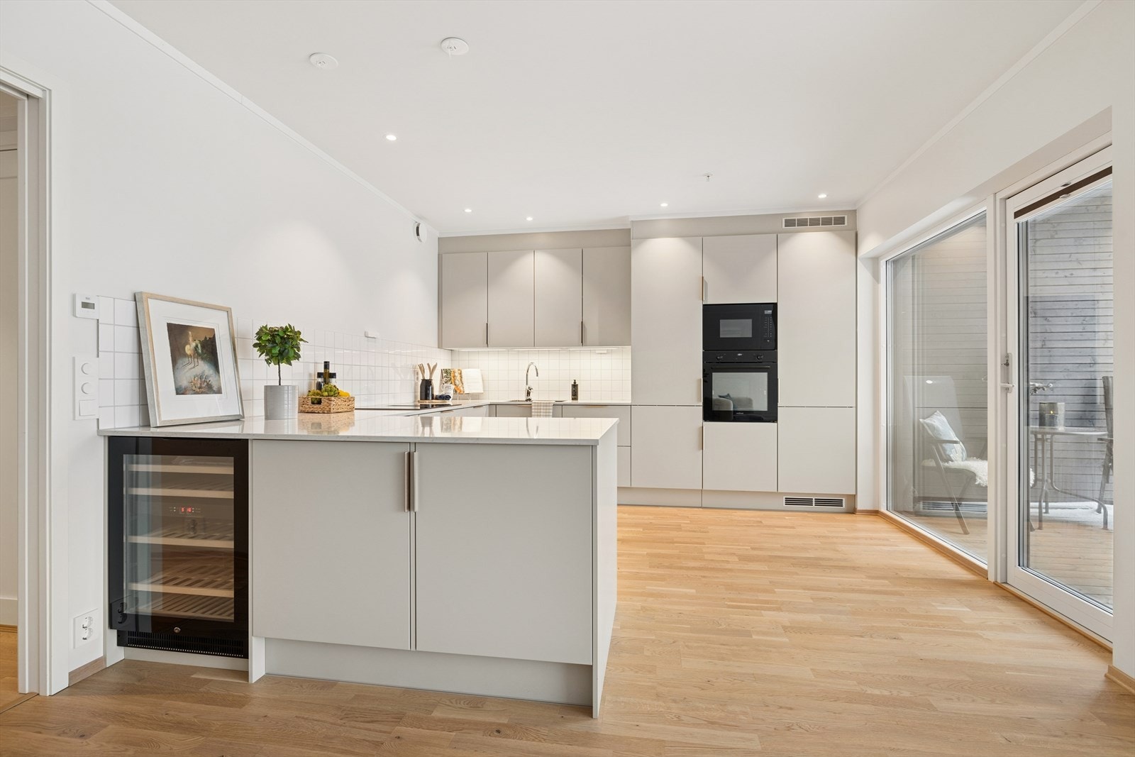 Kjøkkenet har JKE innredning med glatte fronter, benkeplaten er av stein med nedfelt sort vask og det er integrert kjøleskap. Galleribilde