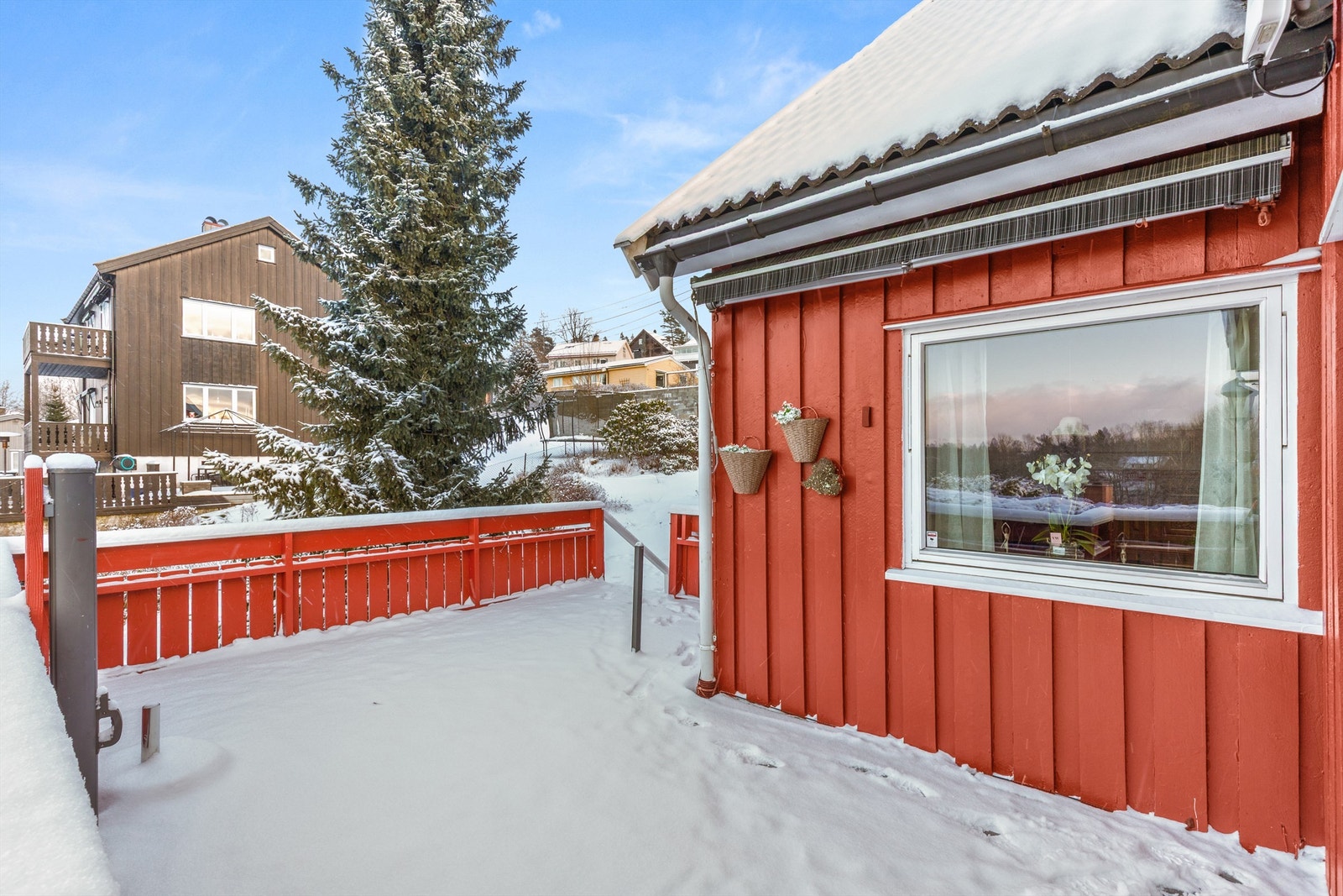 Terrasse med utgang fra vinterhagen i stuen, denne ligger på vestsiden av huset og strekker seg rundt hjørnet mot syd. Vindskjerm montert. Galleribilde