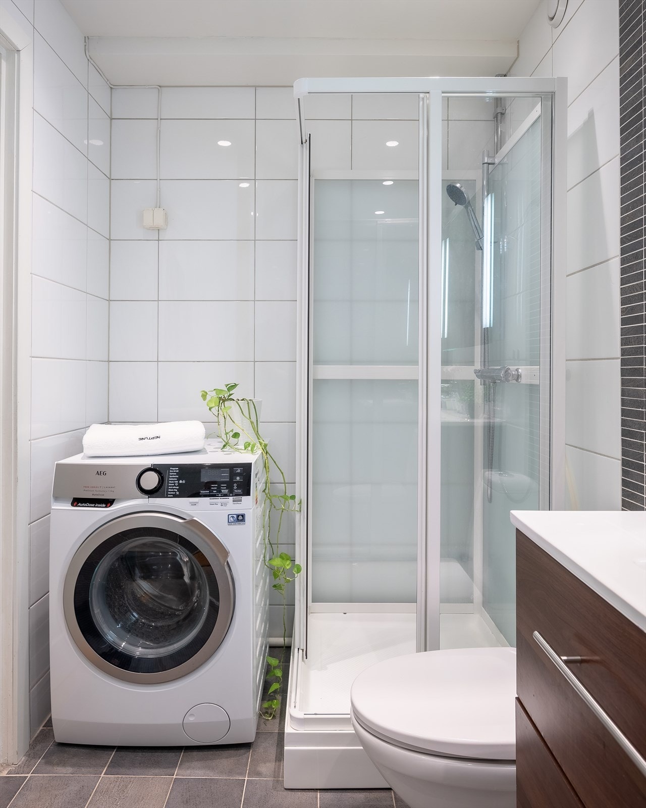 Badet består av gulvstående toalett, dusjkabinett og servant med tilhørende skuffeseksjon. I har badet et praktisk vegghengt skap og speil med integrert belysning. Galleribilde