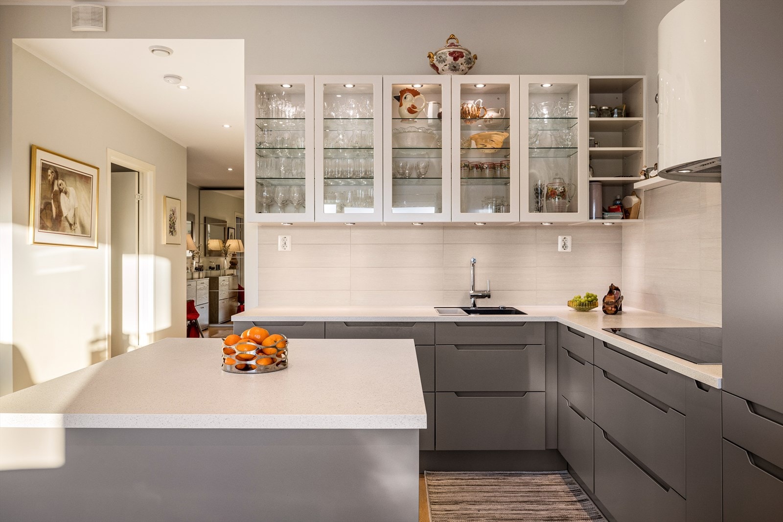 Kjøkkenet har gjennomtenkte oppbevaringsløsninger med under- og overskap, kjøkkenøy og overskap med glassfronter, glasshyller med belysning. Galleribilde