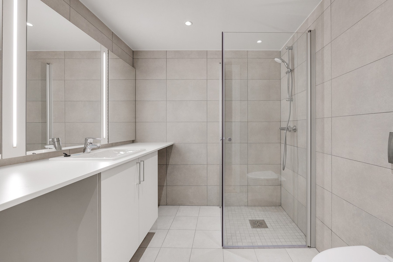 Romslig og delikat bad med flislagte overflater og varmekabler i gulv. Galleribilde